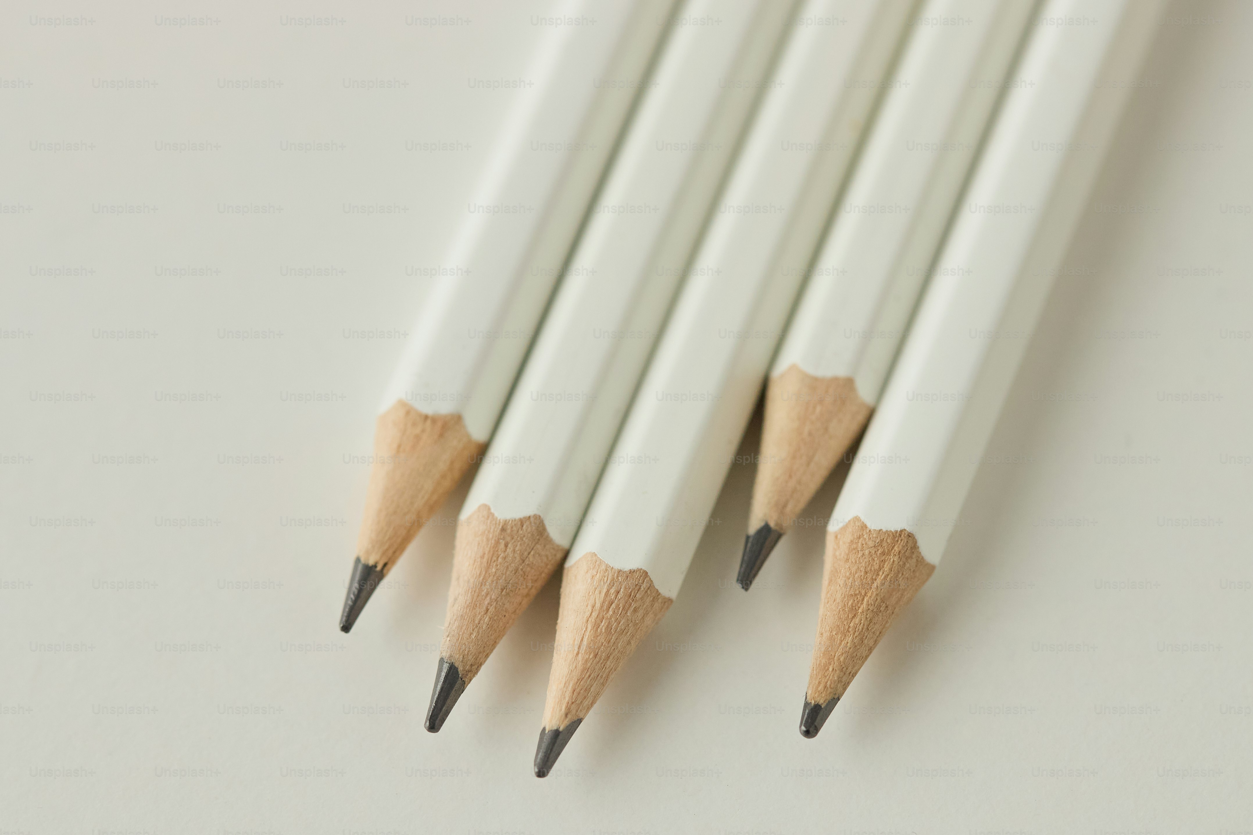 Several sharpened white pencils on a light background