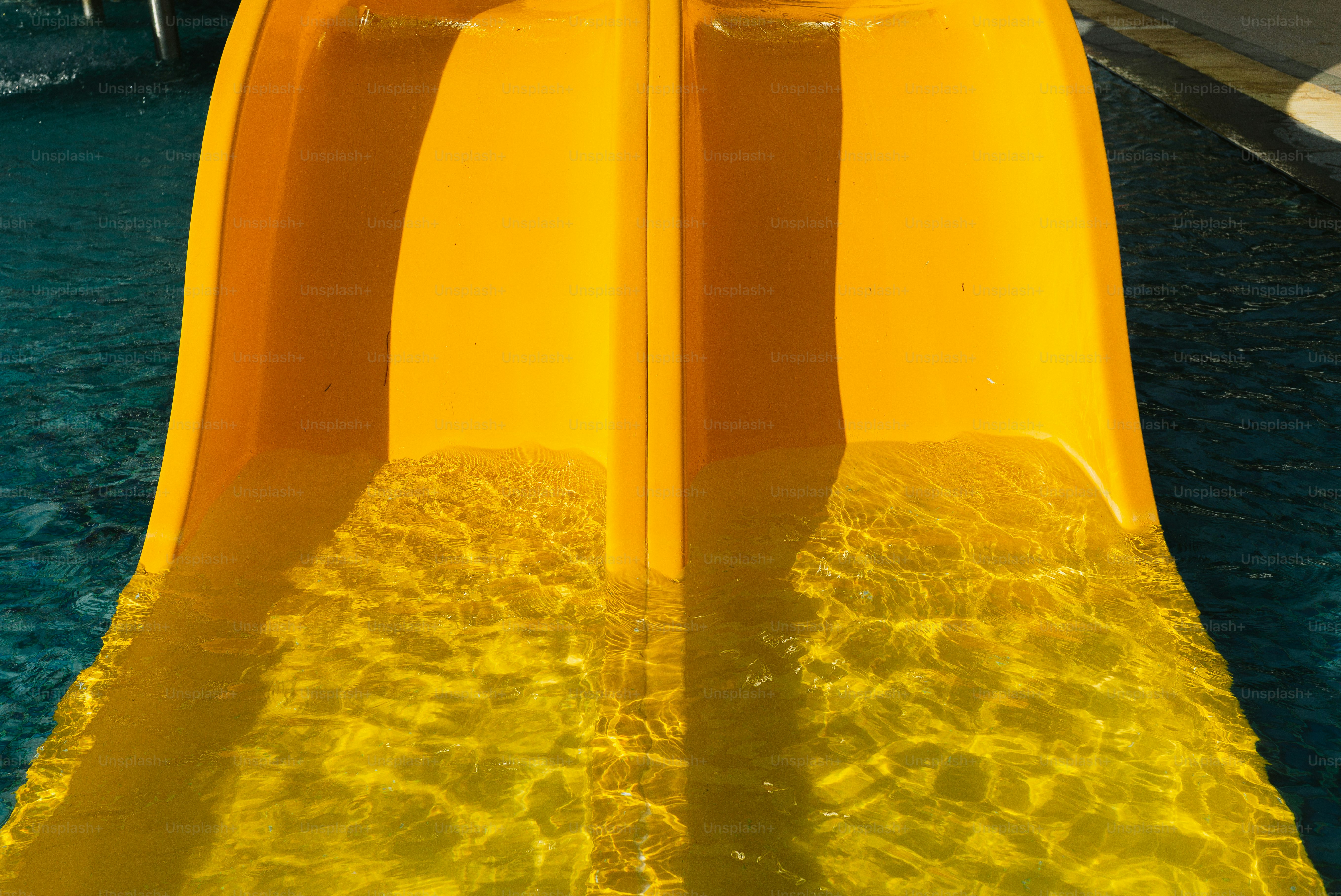 Yellow water slide entering pool water