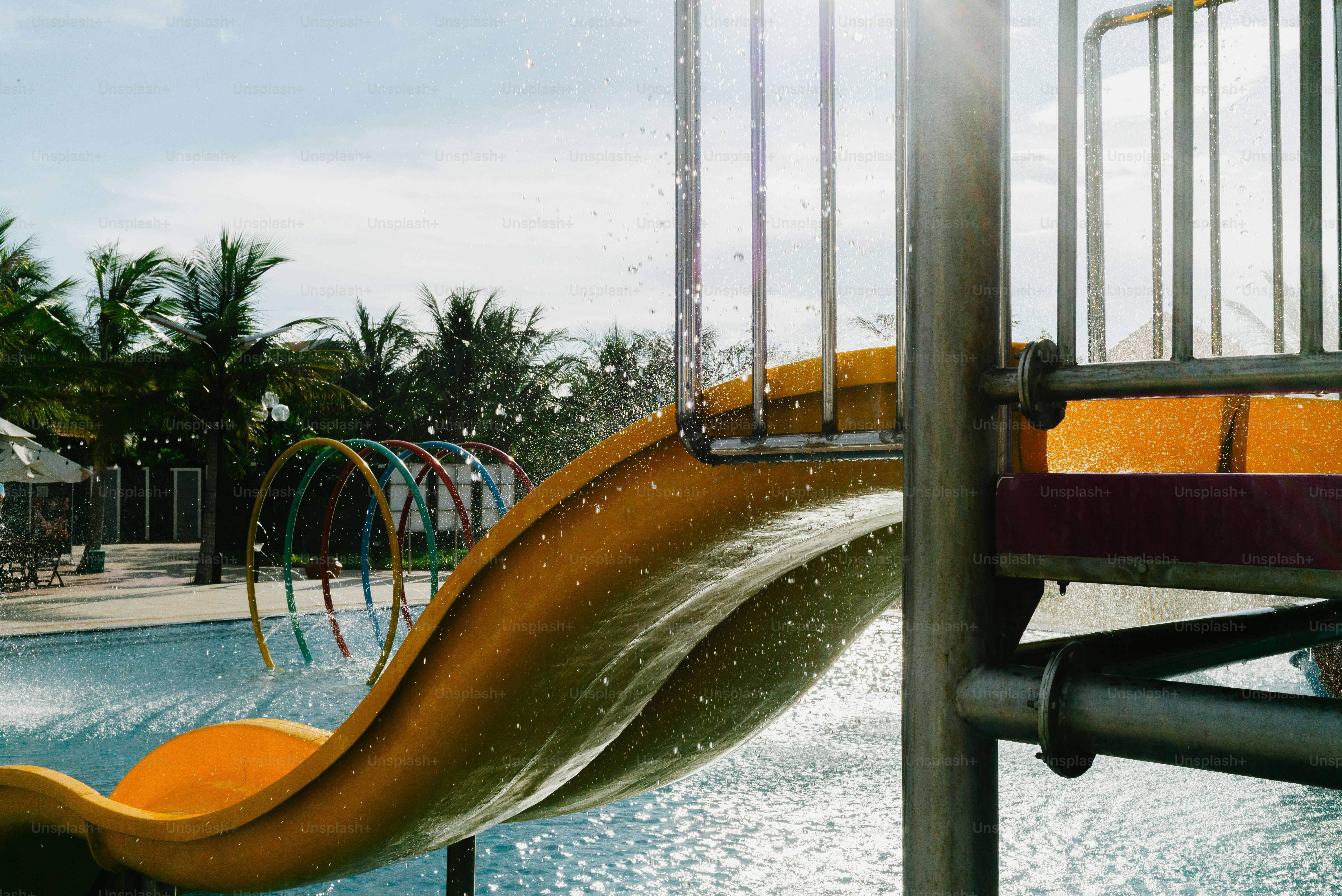 Water splashes down a yellow slide at a pool.