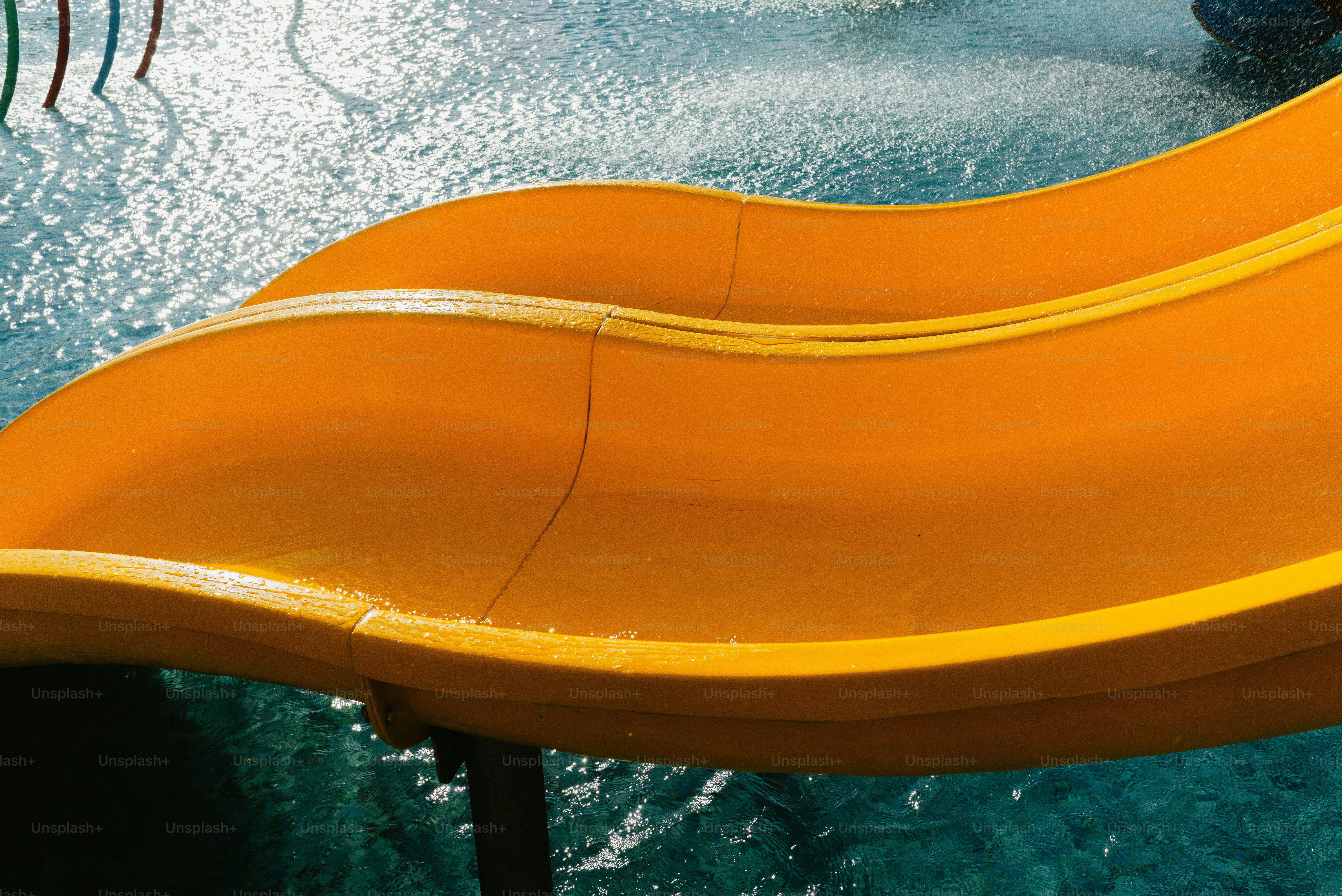 Bright orange water slide curving over pool