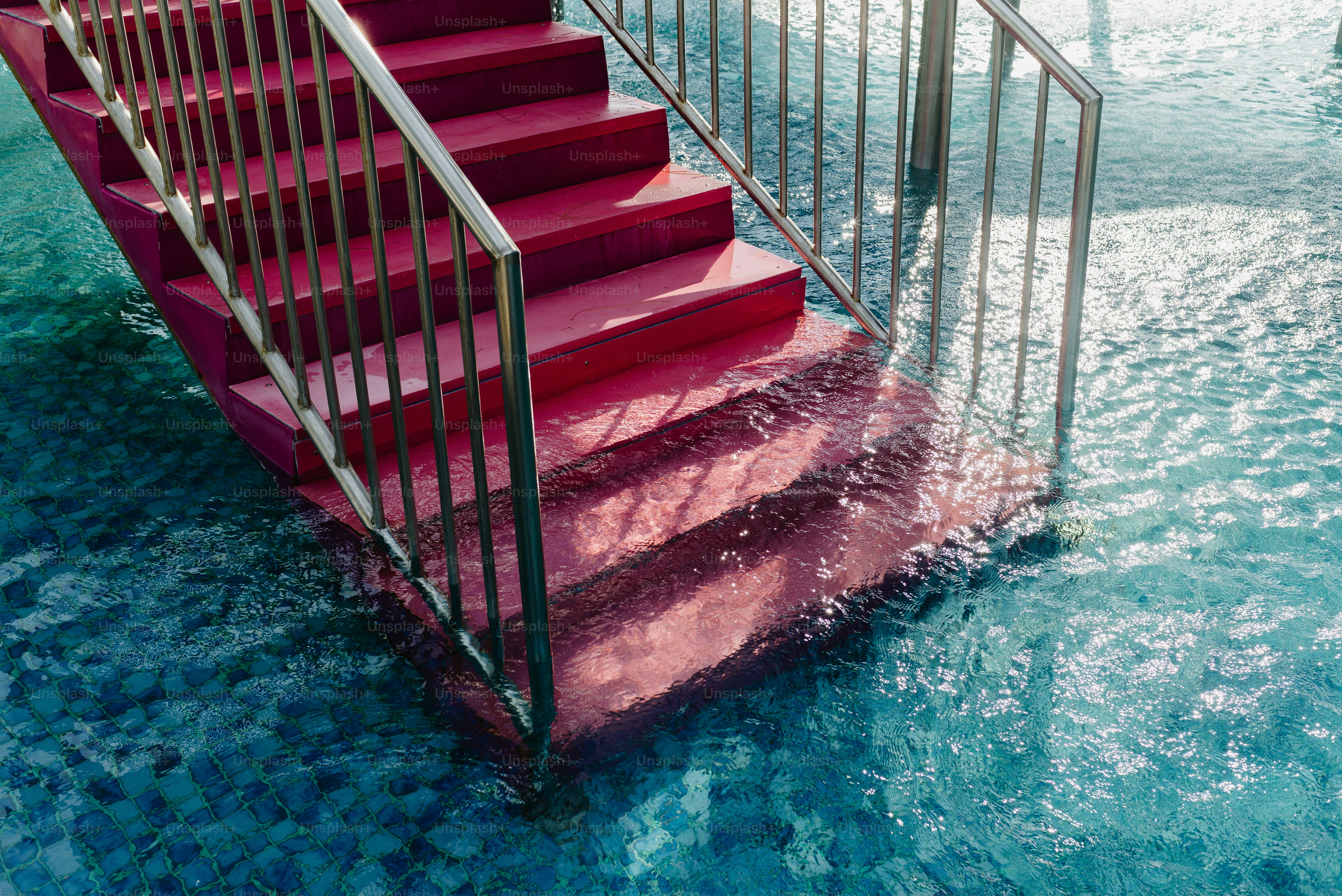 Red stairs submerged in clear blue water