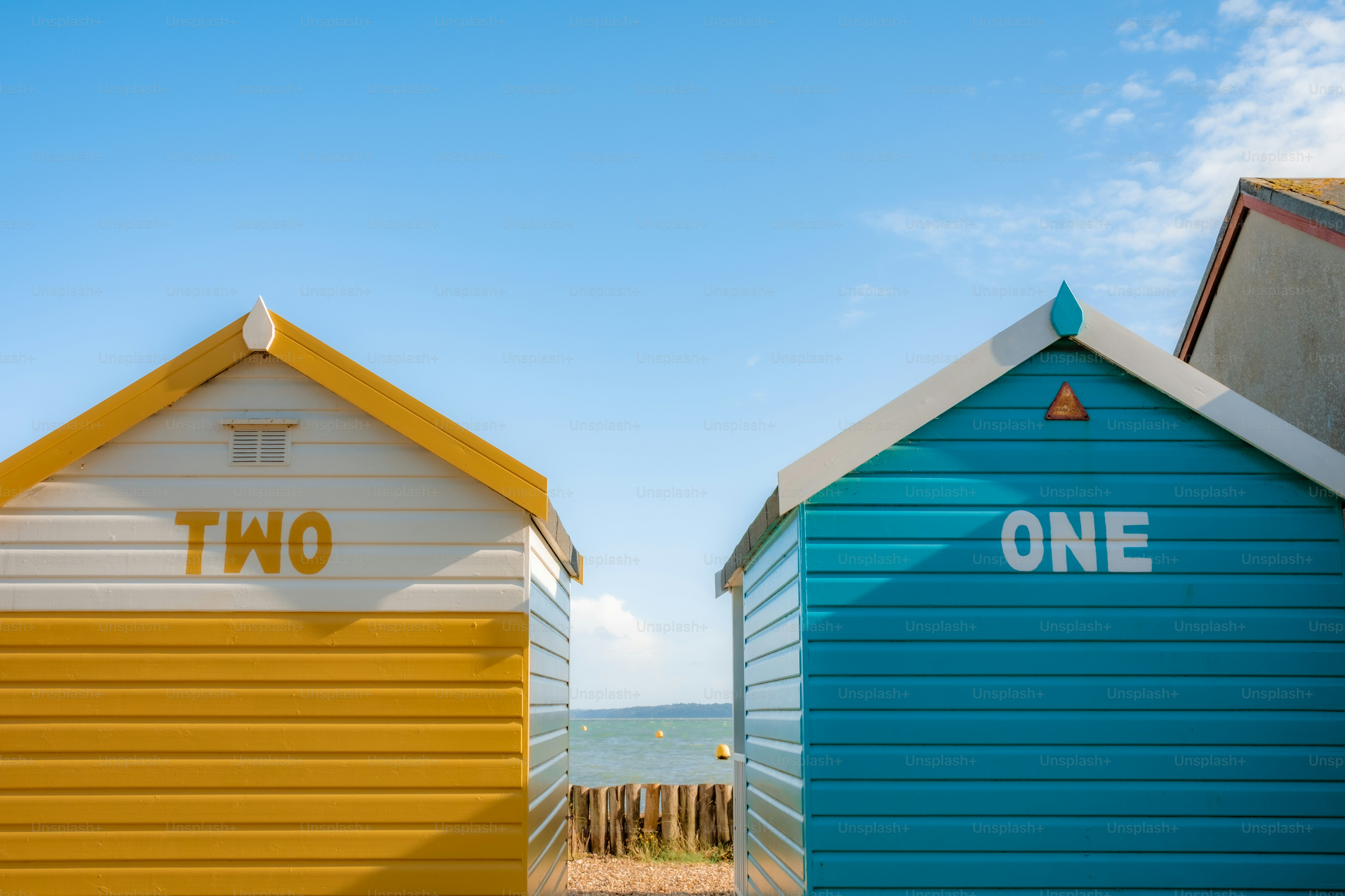 Dos coloridas cabañas de playa contra un cielo azul.