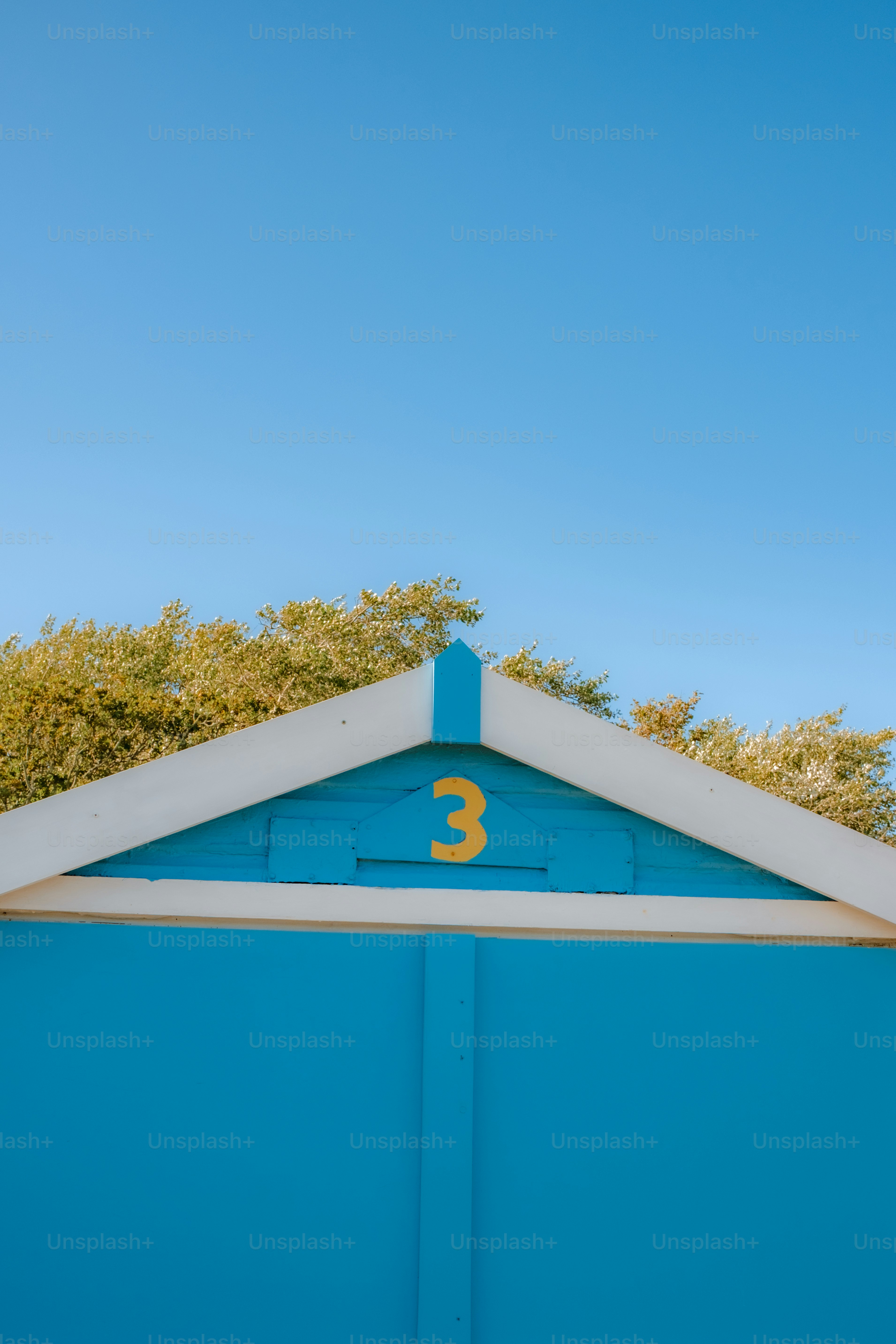 Bright blue beach hut with yellow number three.