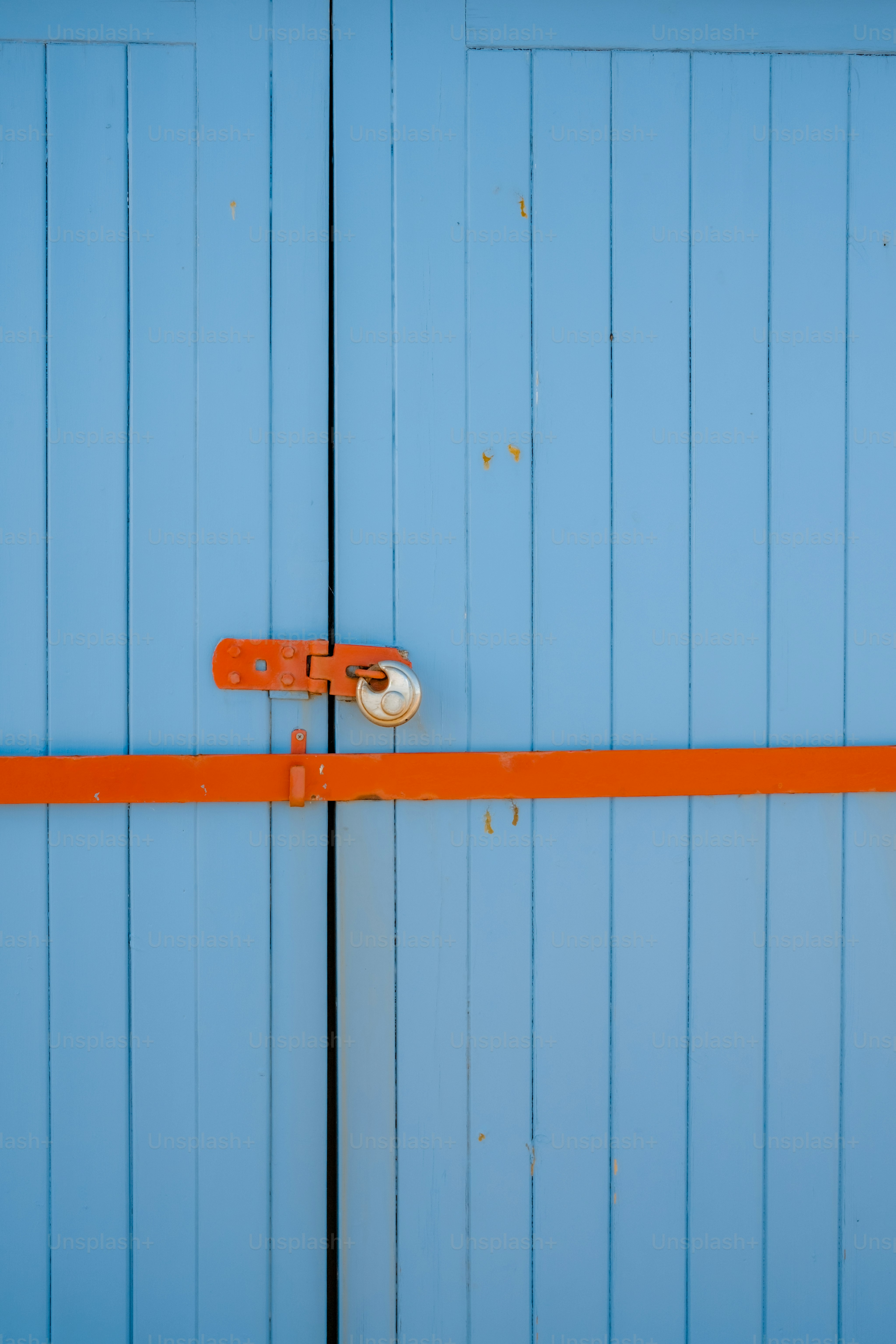 Blue wooden doors secured with orange lock and bar