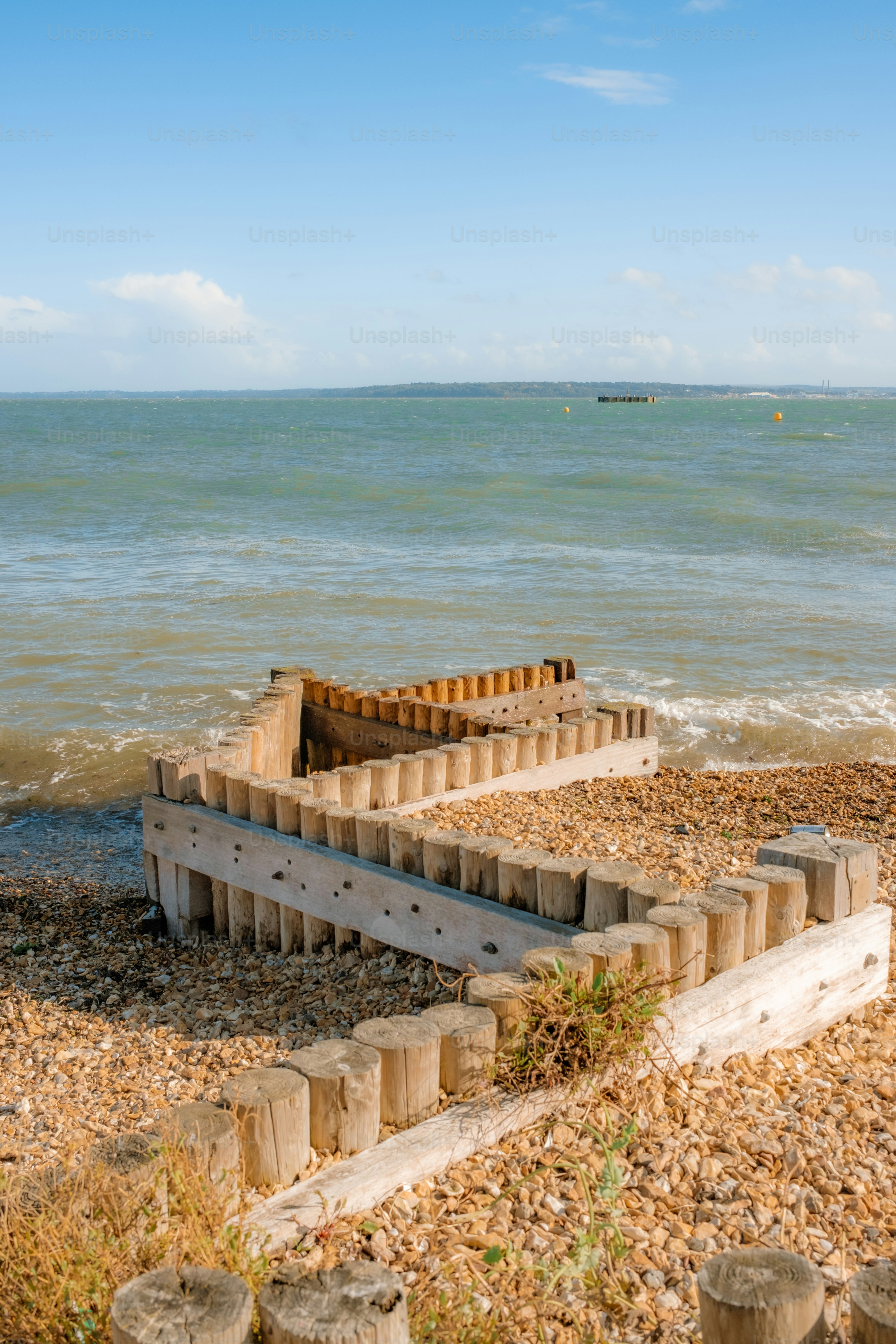 Estructura de defensa marítima de madera en una playa de guijarros.