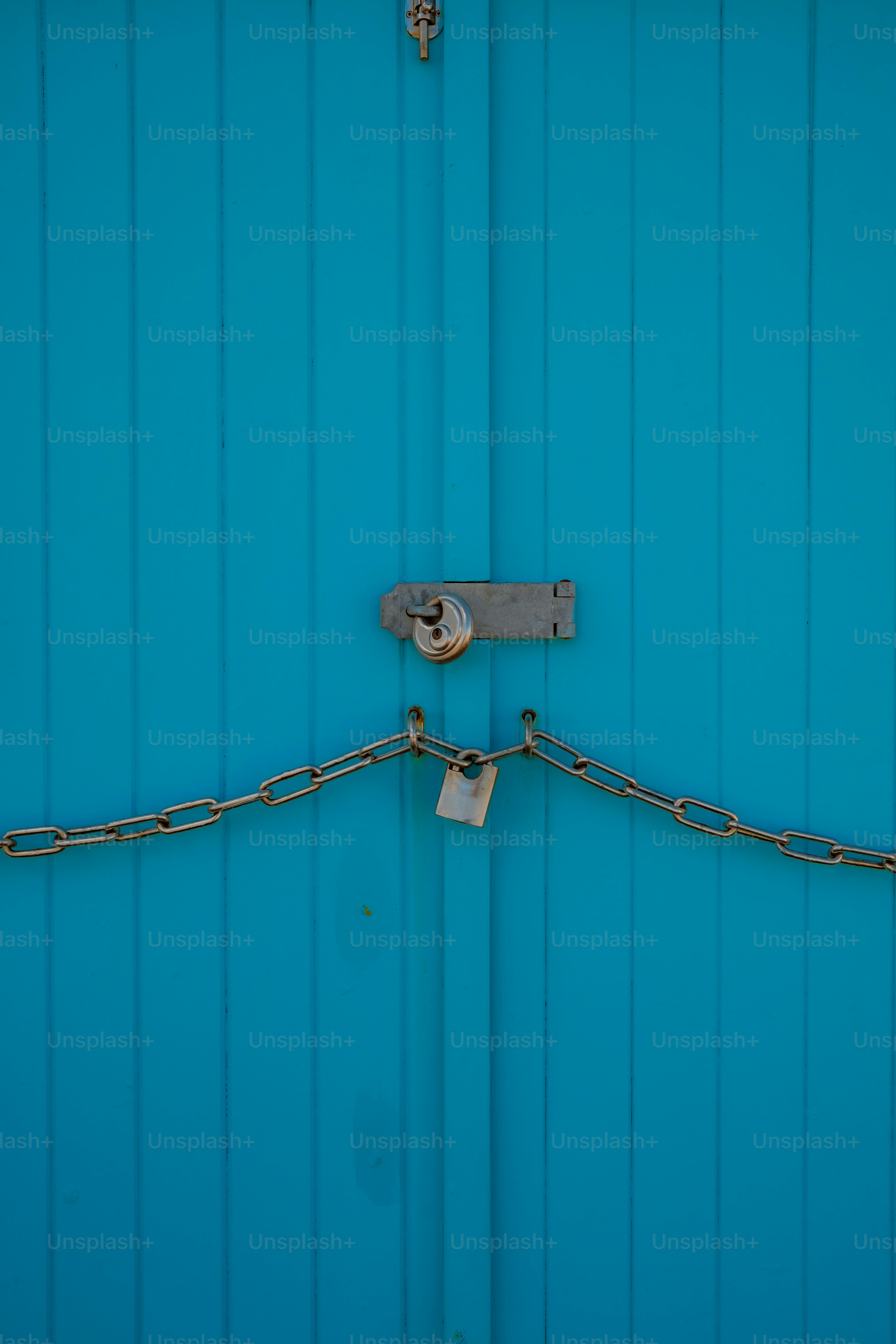 Pintu biru cerah diamankan dengan rantai dan kunci