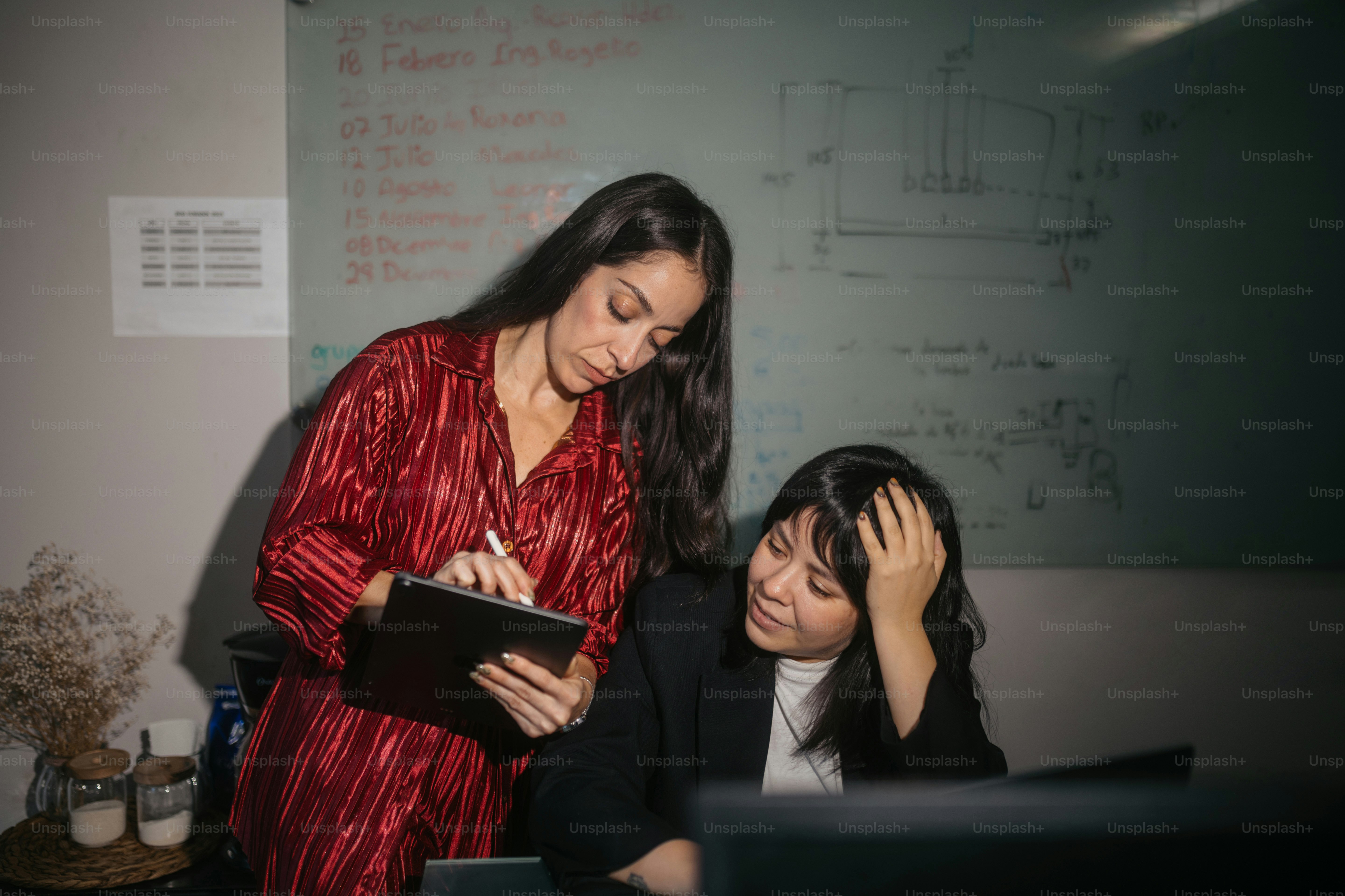 Two women collaborating at a desk with a whiteboard