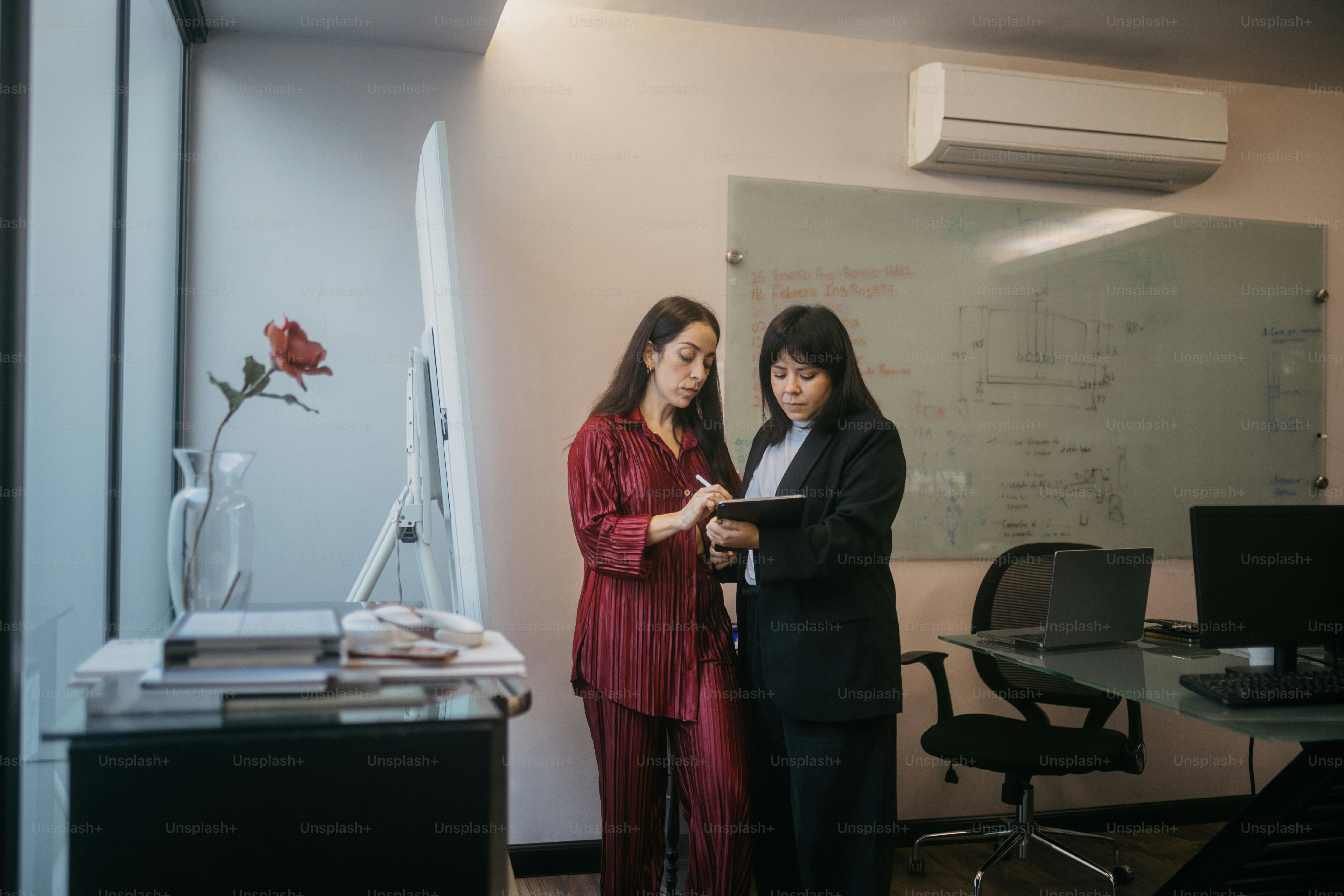 Two women discussing a tablet in an office
