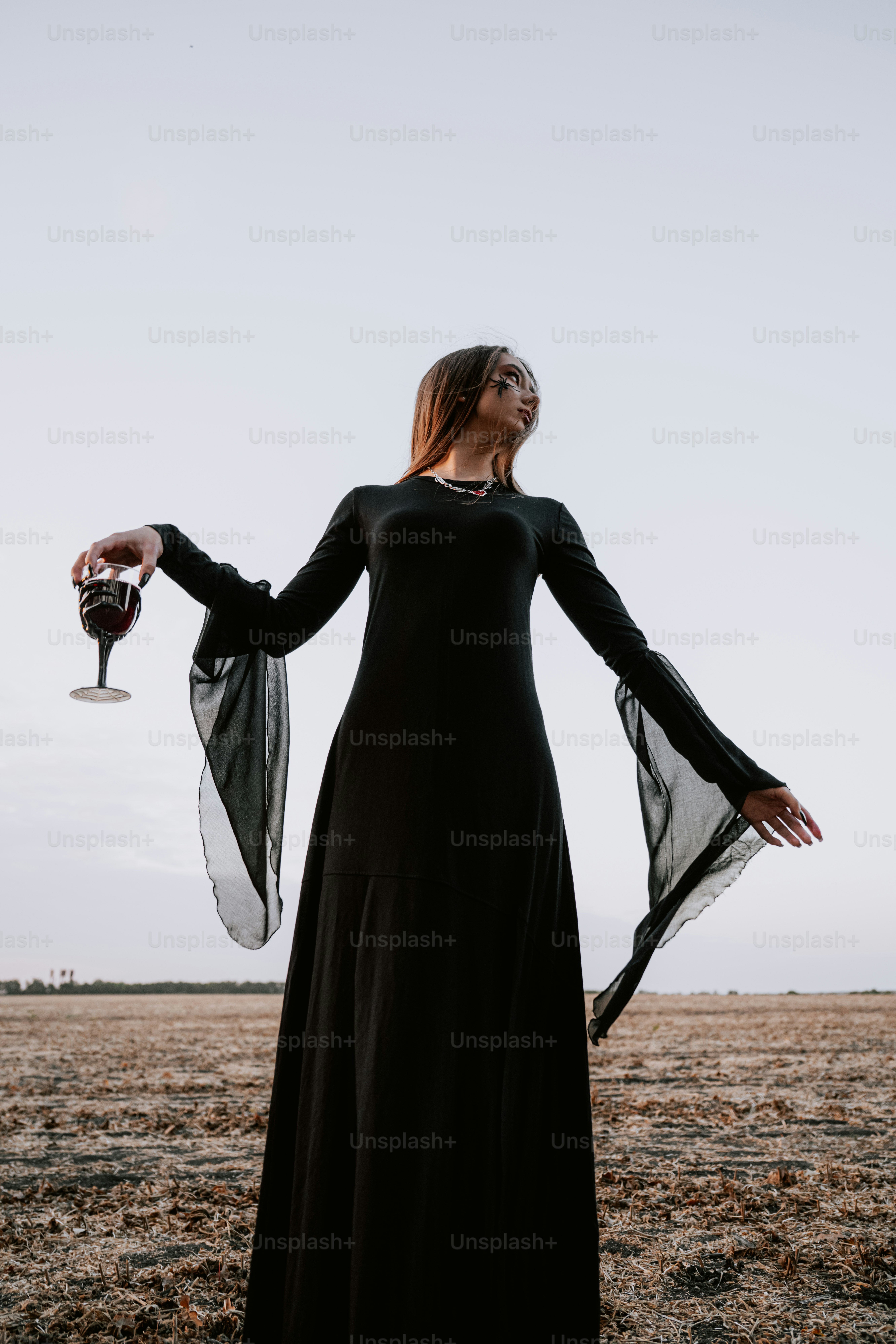 Woman in black dress holding a wine glass outdoors