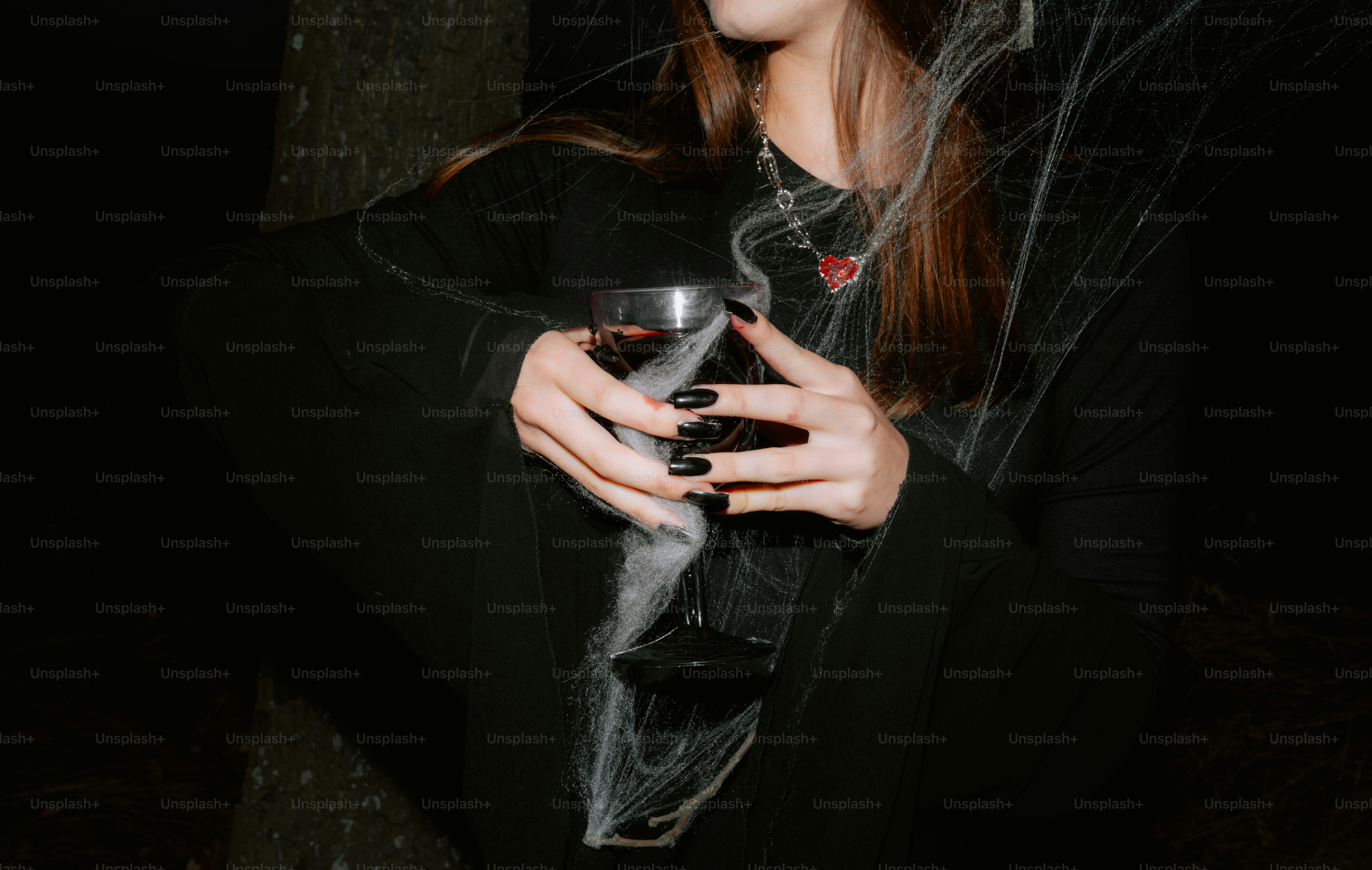 Woman in dark holding glass with cobwebs