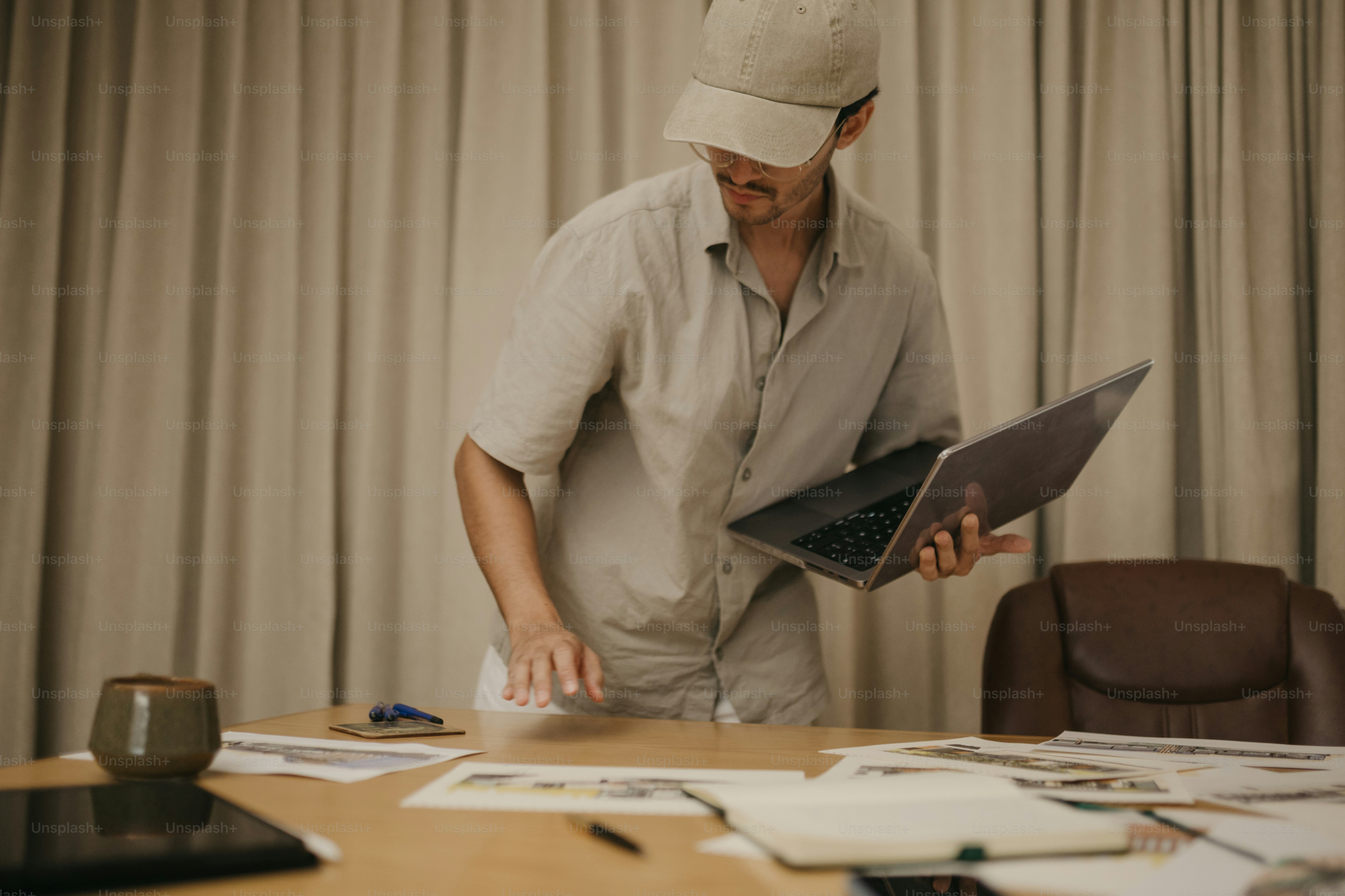 Man in cap working on laptop at messy desk