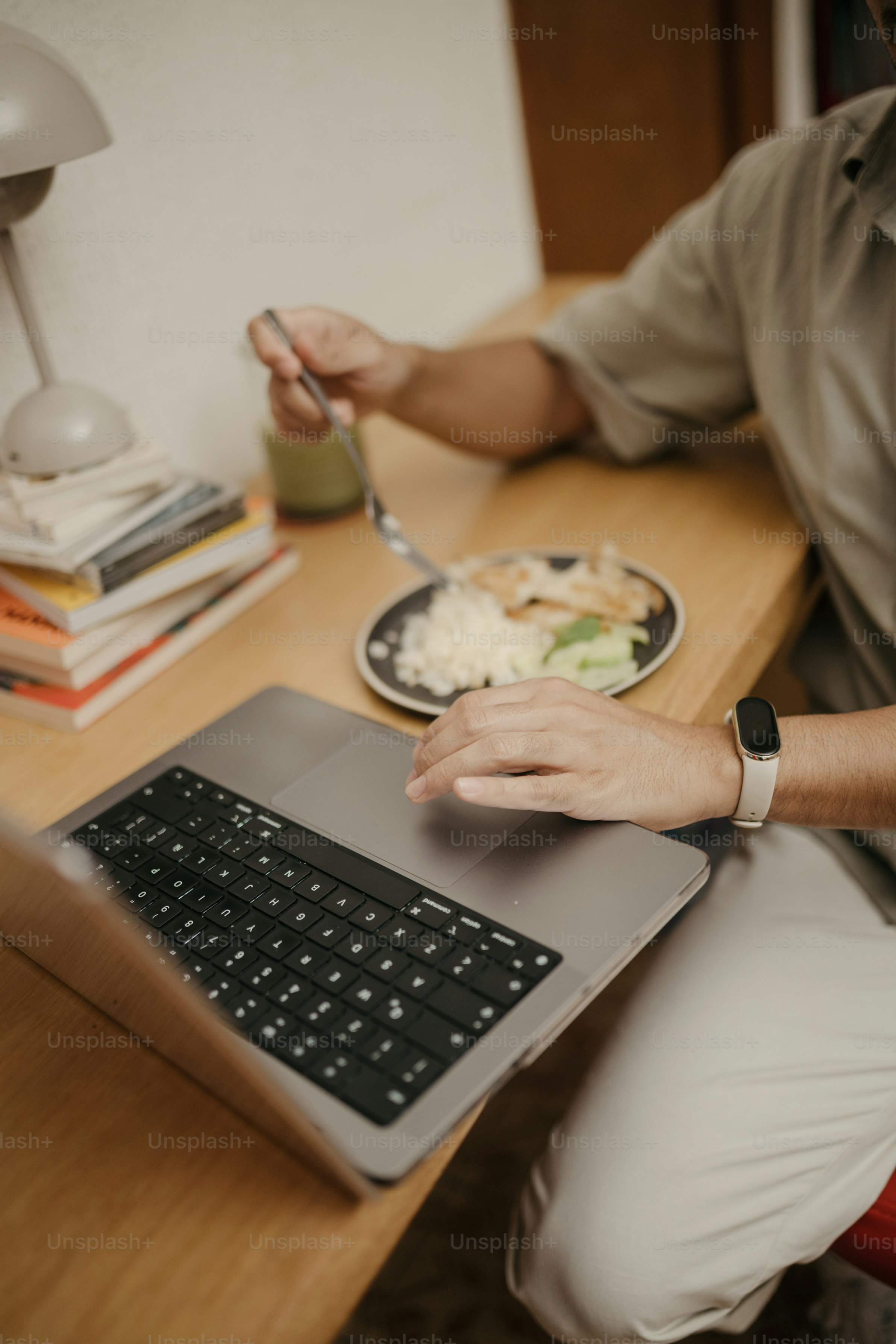 Person eating meal while working on laptop