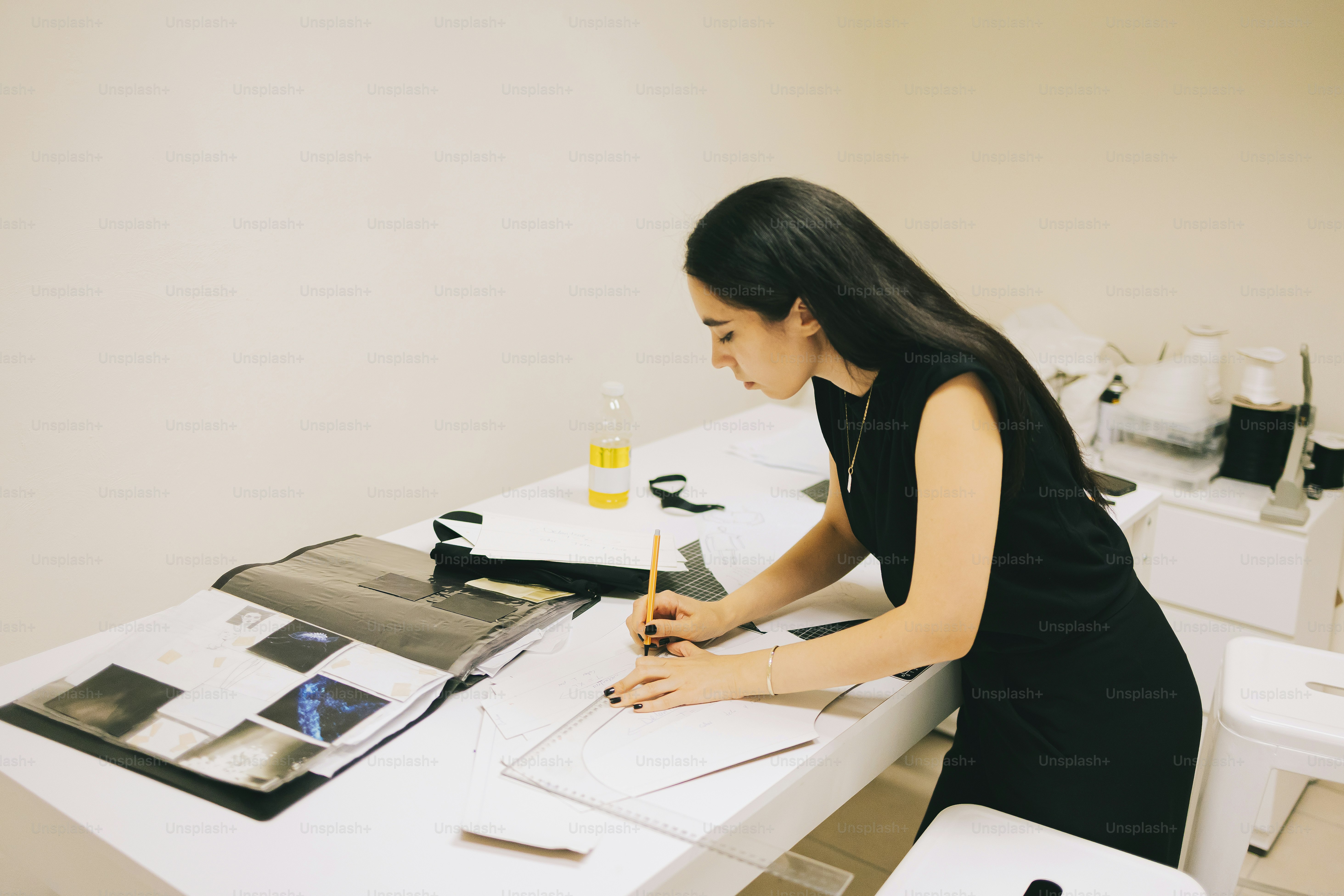 Woman sketching at a table with fabric swatches.
