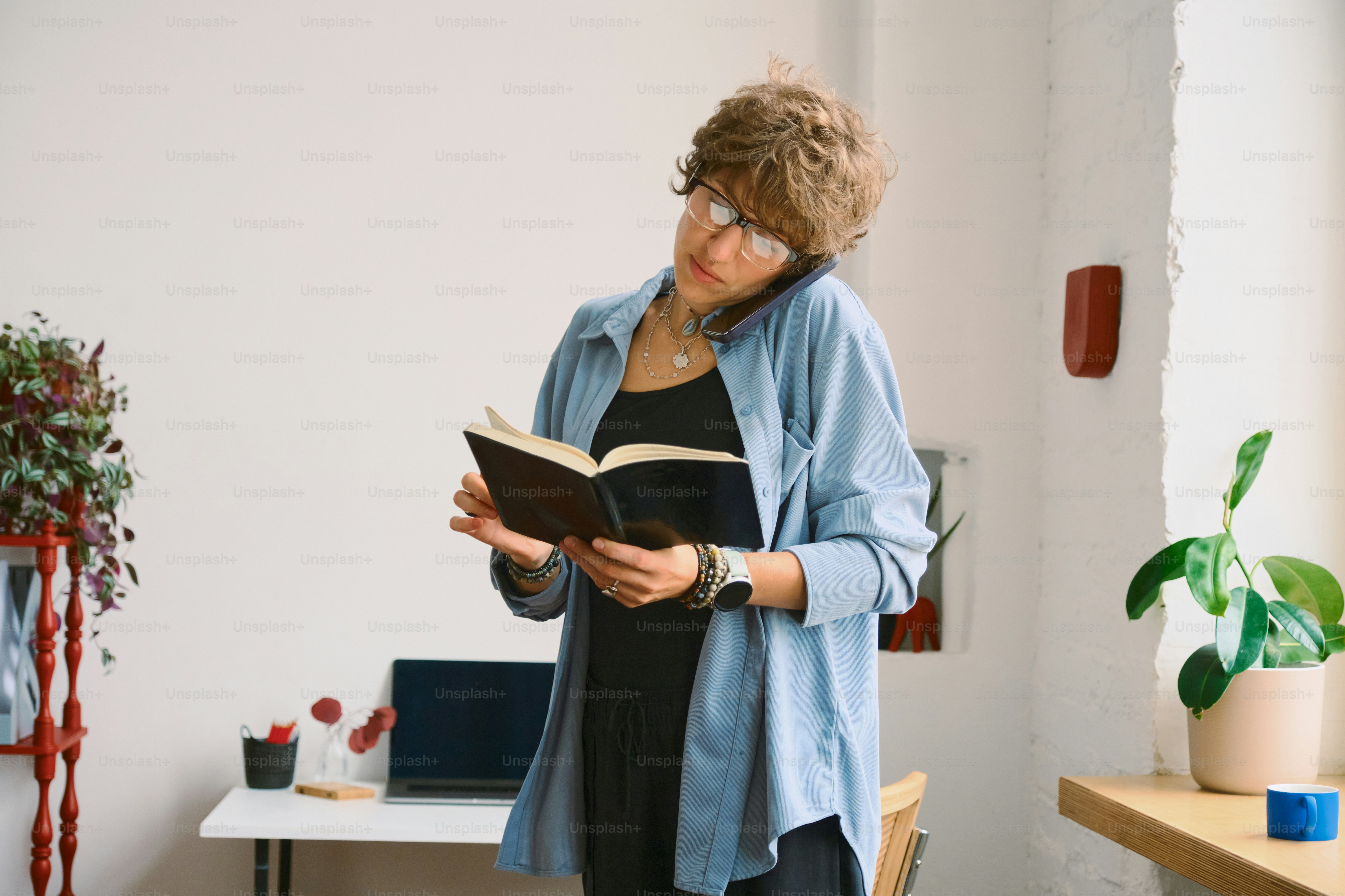 Mulher falando ao telefone enquanto lê um livro.
