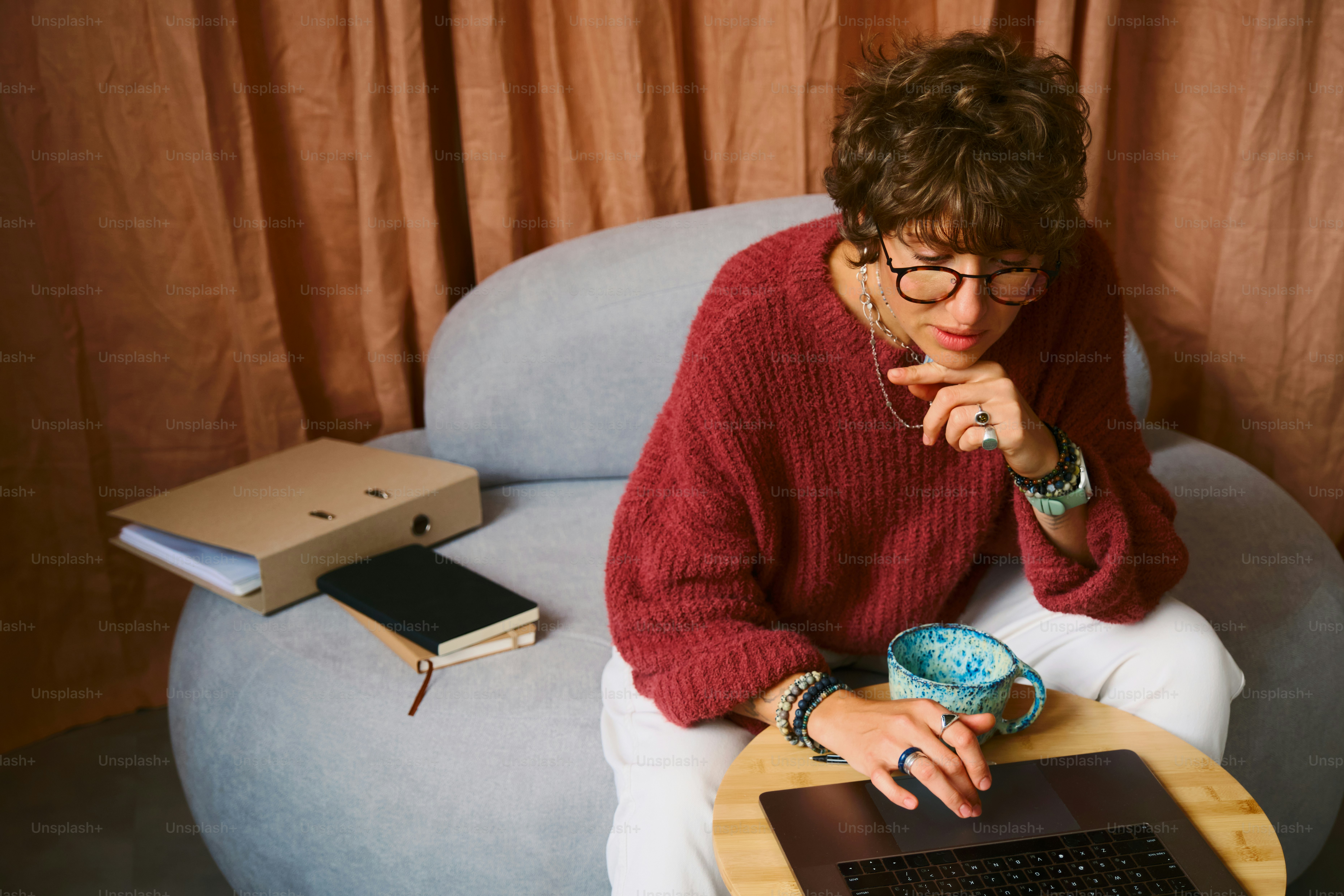 Uomo che lavora sul computer portatile in accogliente poltrona con caffè.