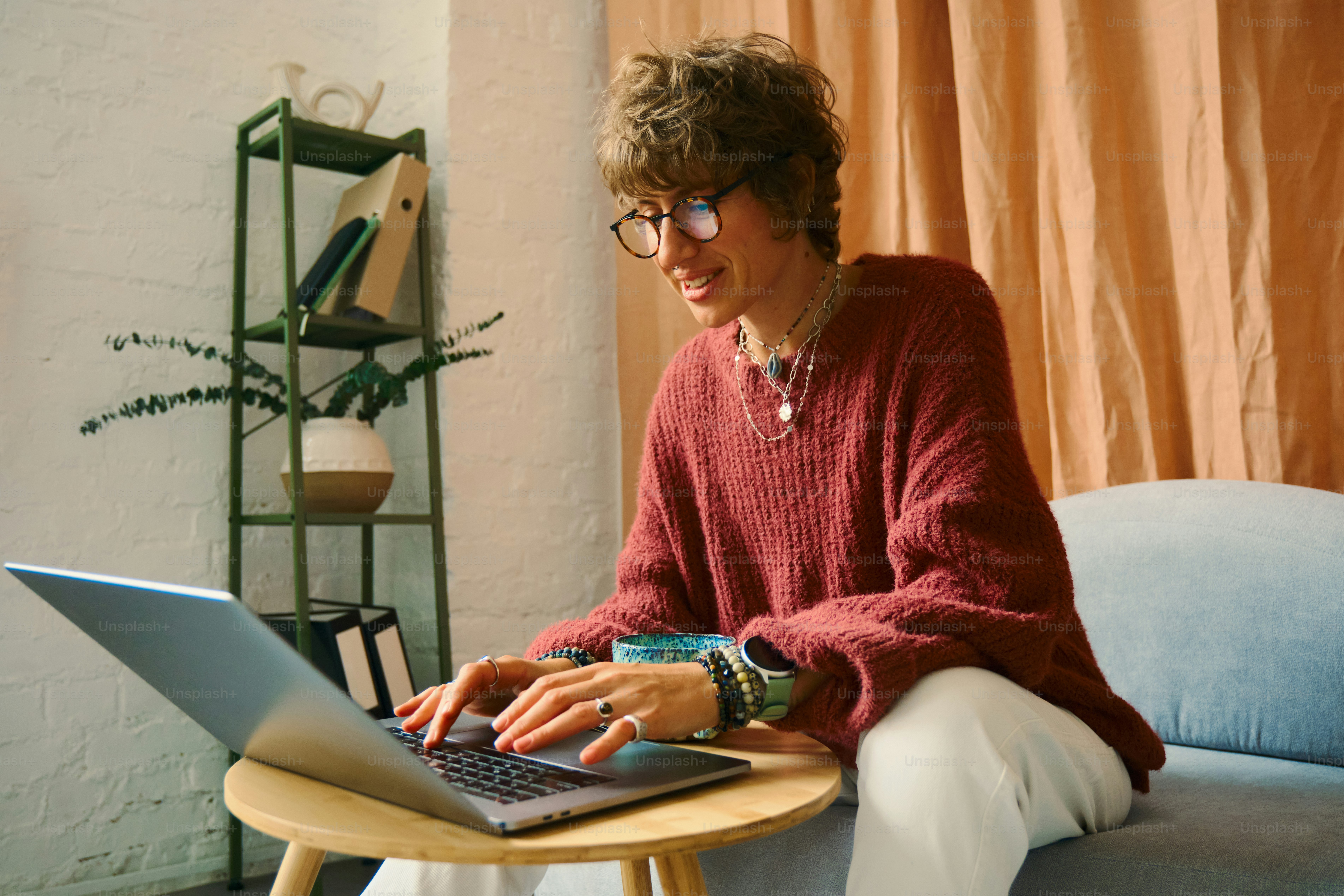 Mulher com cabelo encaracolado digitando no laptop em casa.