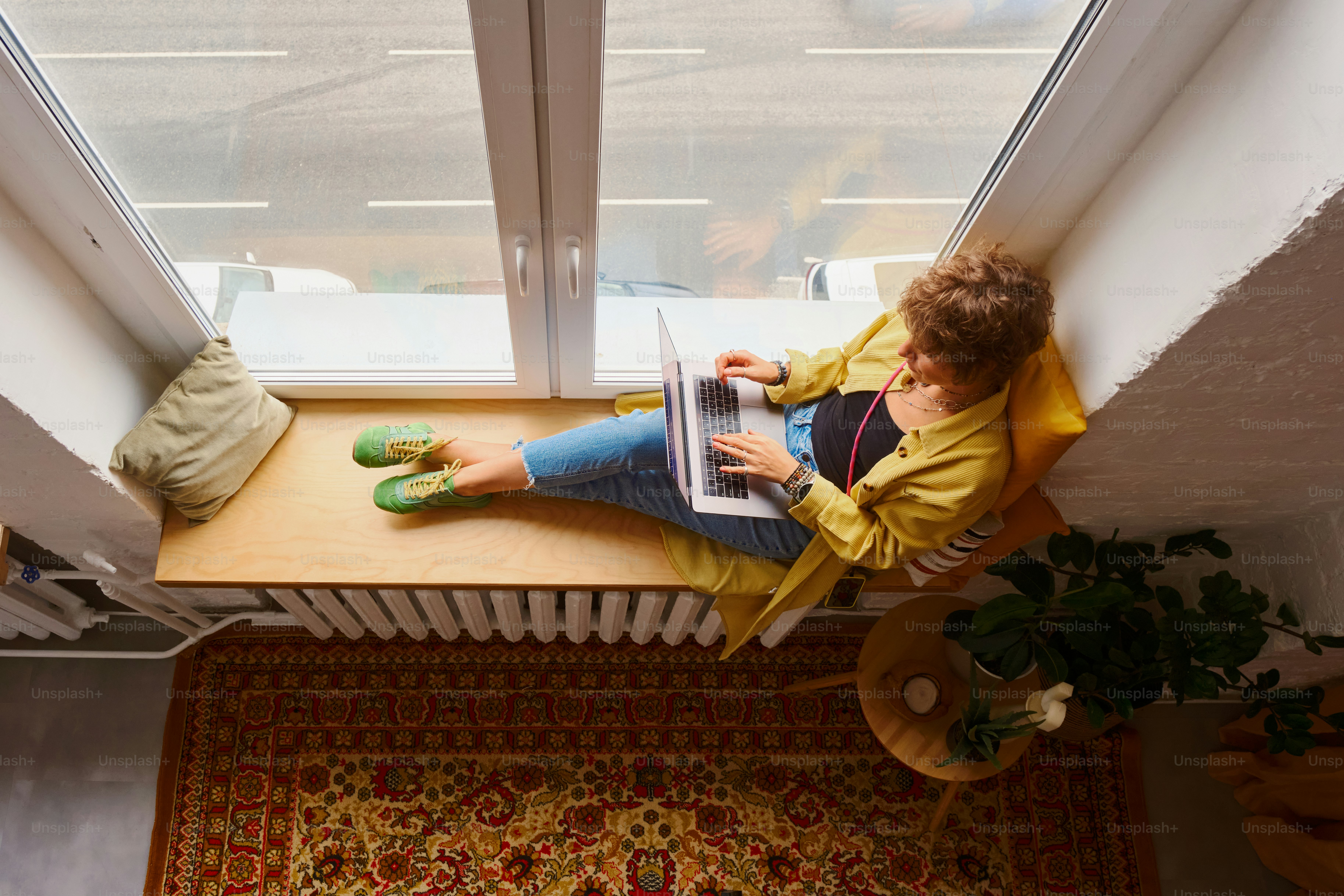 Mulher trabalhando no laptop por uma grande janela.