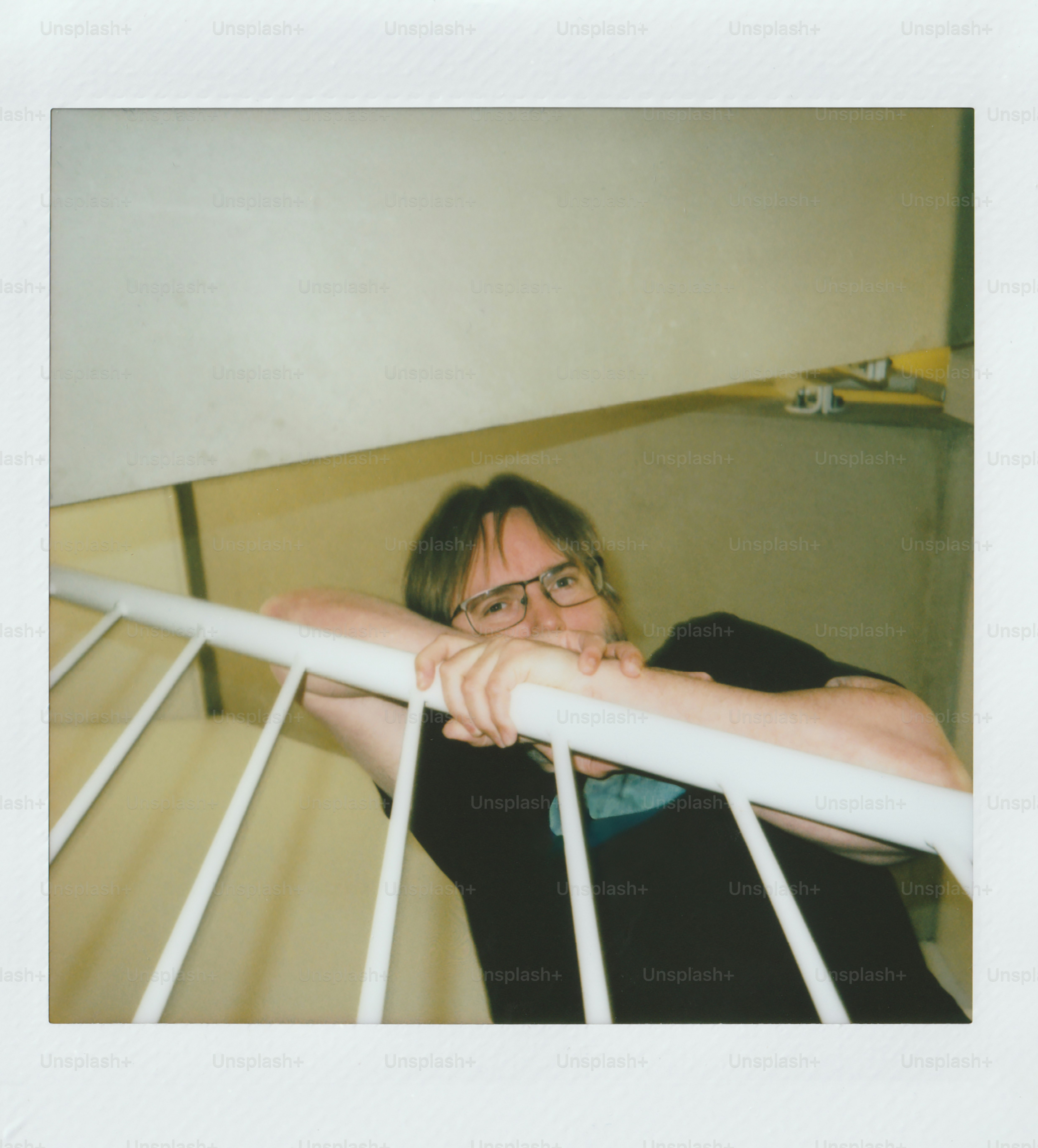 Man with glasses leans on a white railing.