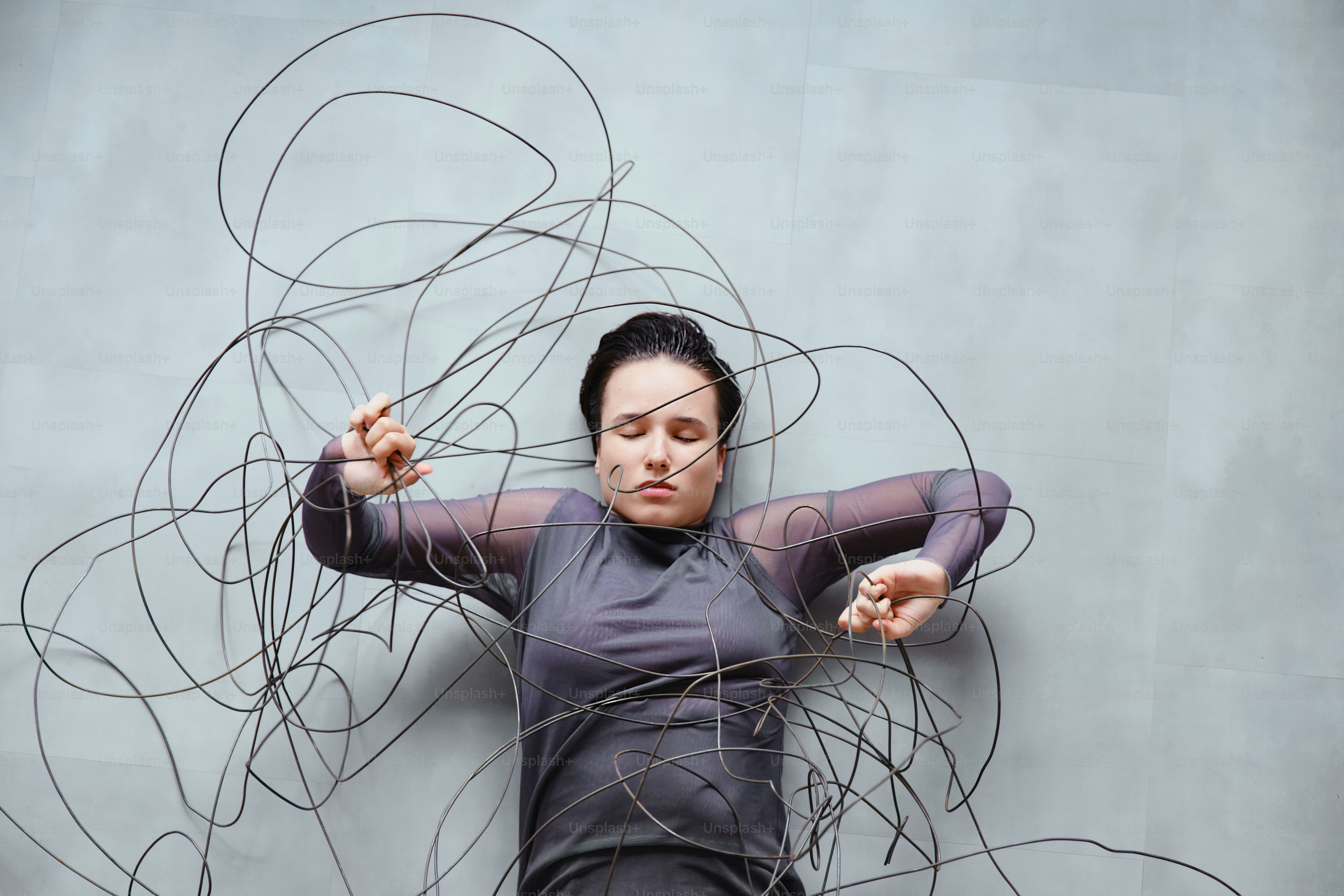 Donna aggrovigliata in fili su sfondo grigio