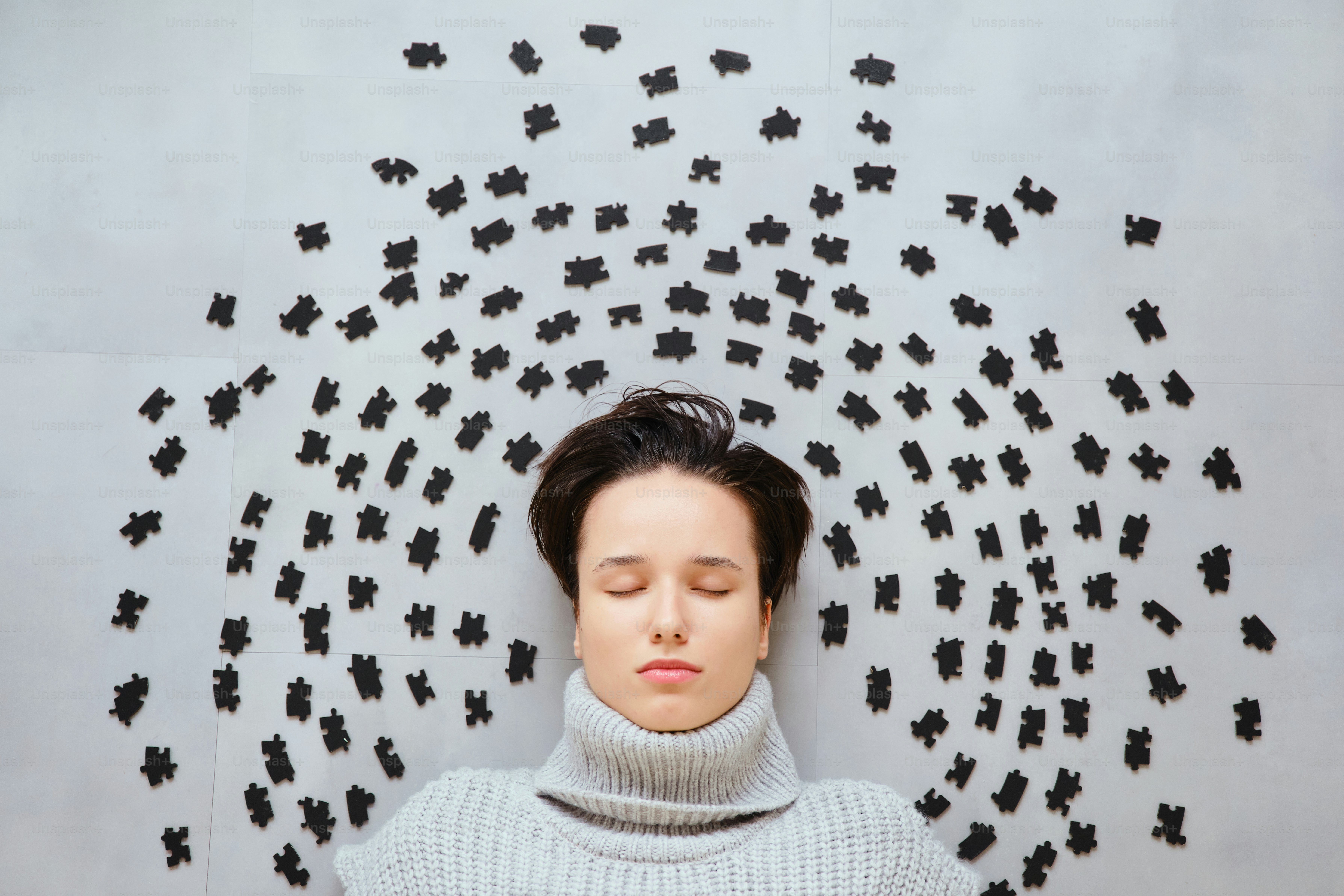 Woman with eyes closed surrounded by scattered puzzle pieces