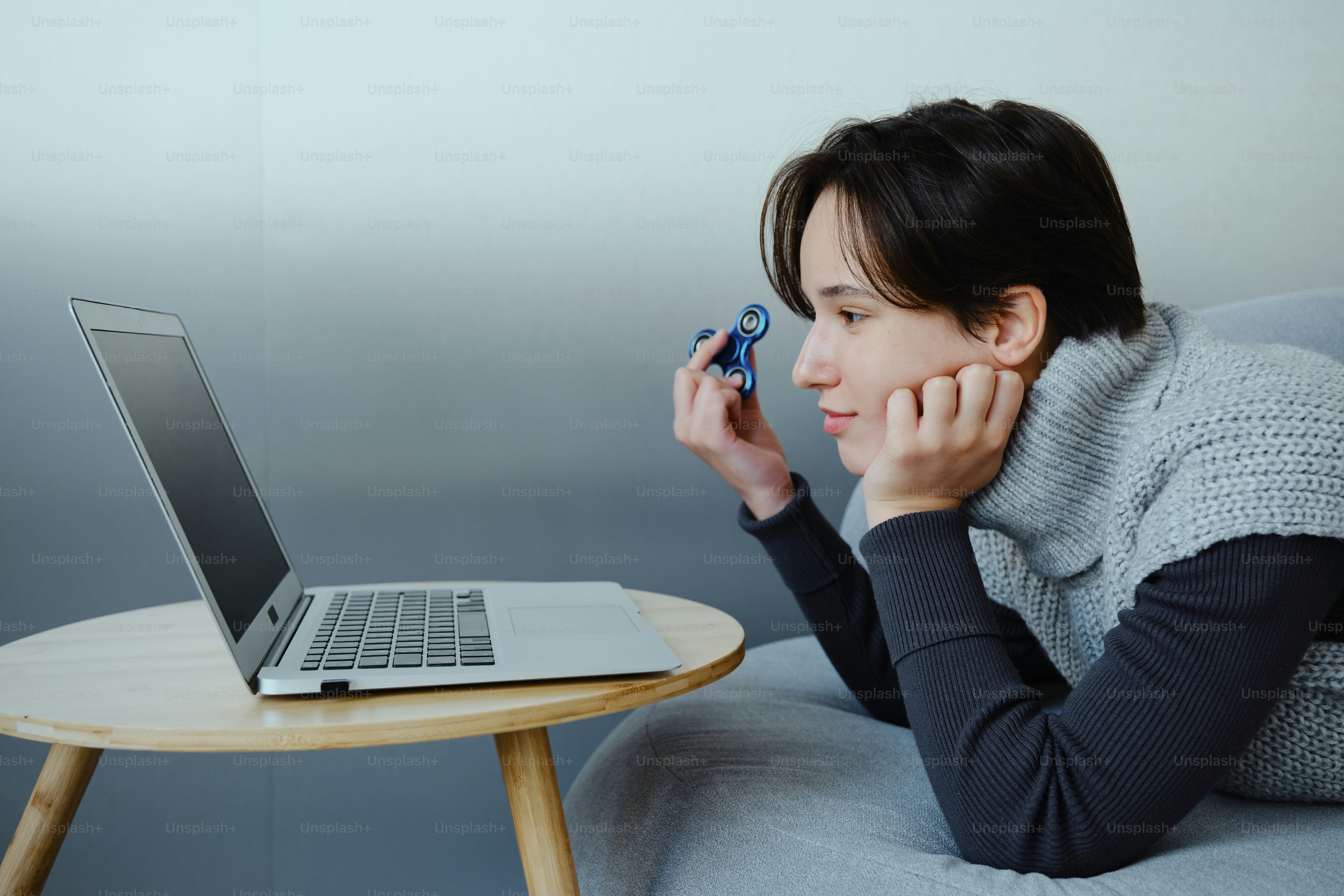 A person lies on a couch looking at a laptop.