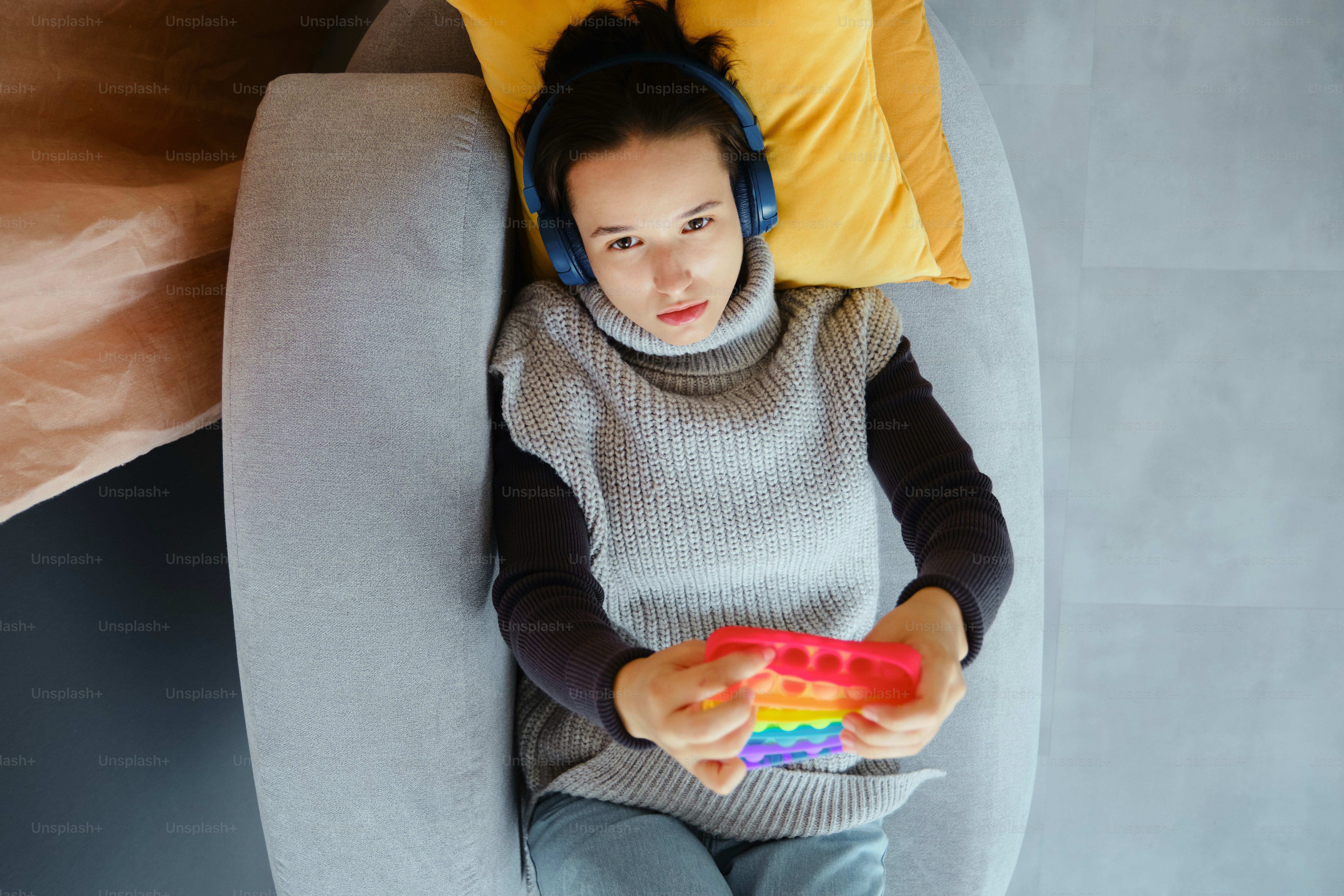 Une femme avec des écouteurs joue avec un jouet pop-it.