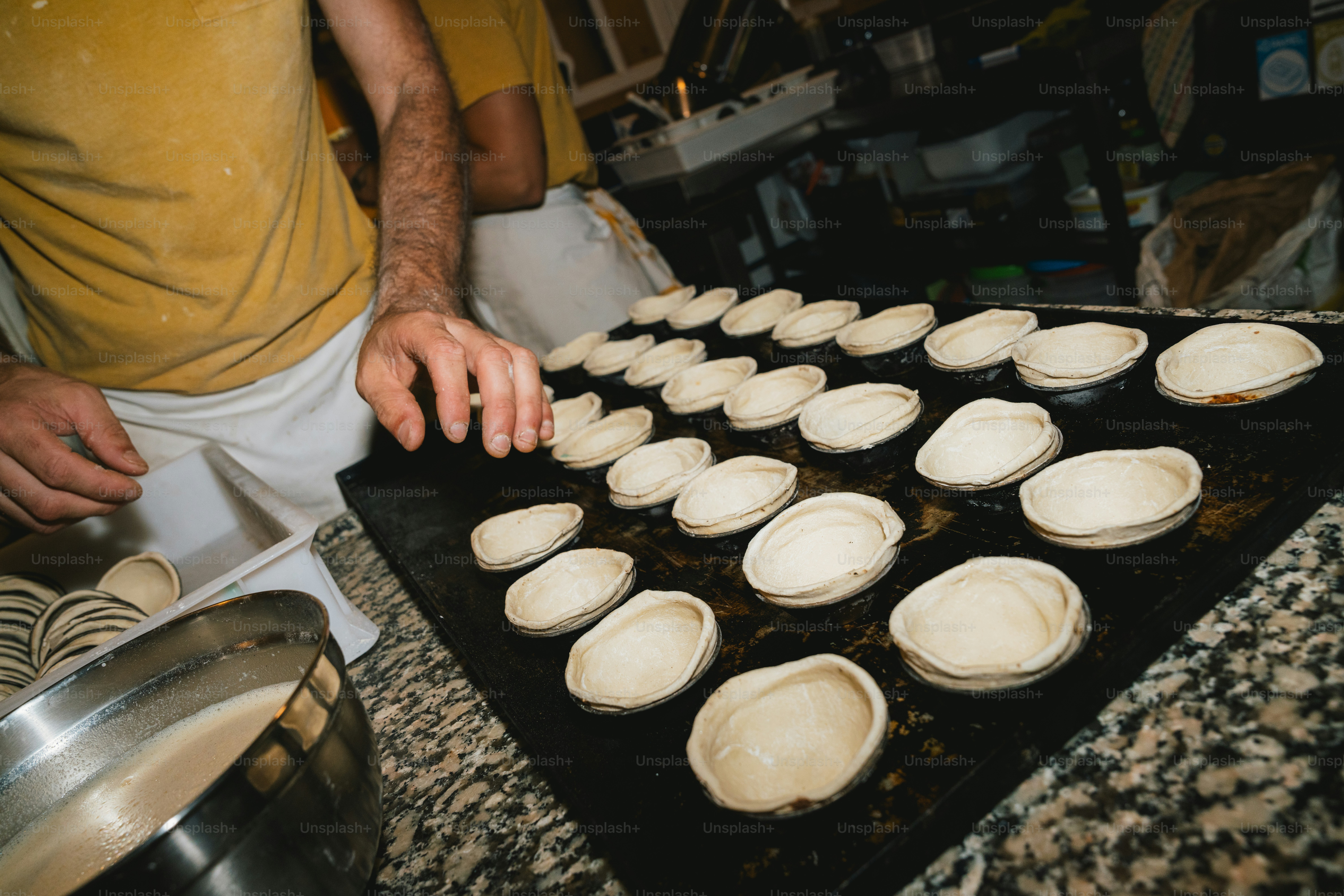 Baker arranging pastry shells on a baking sheet.