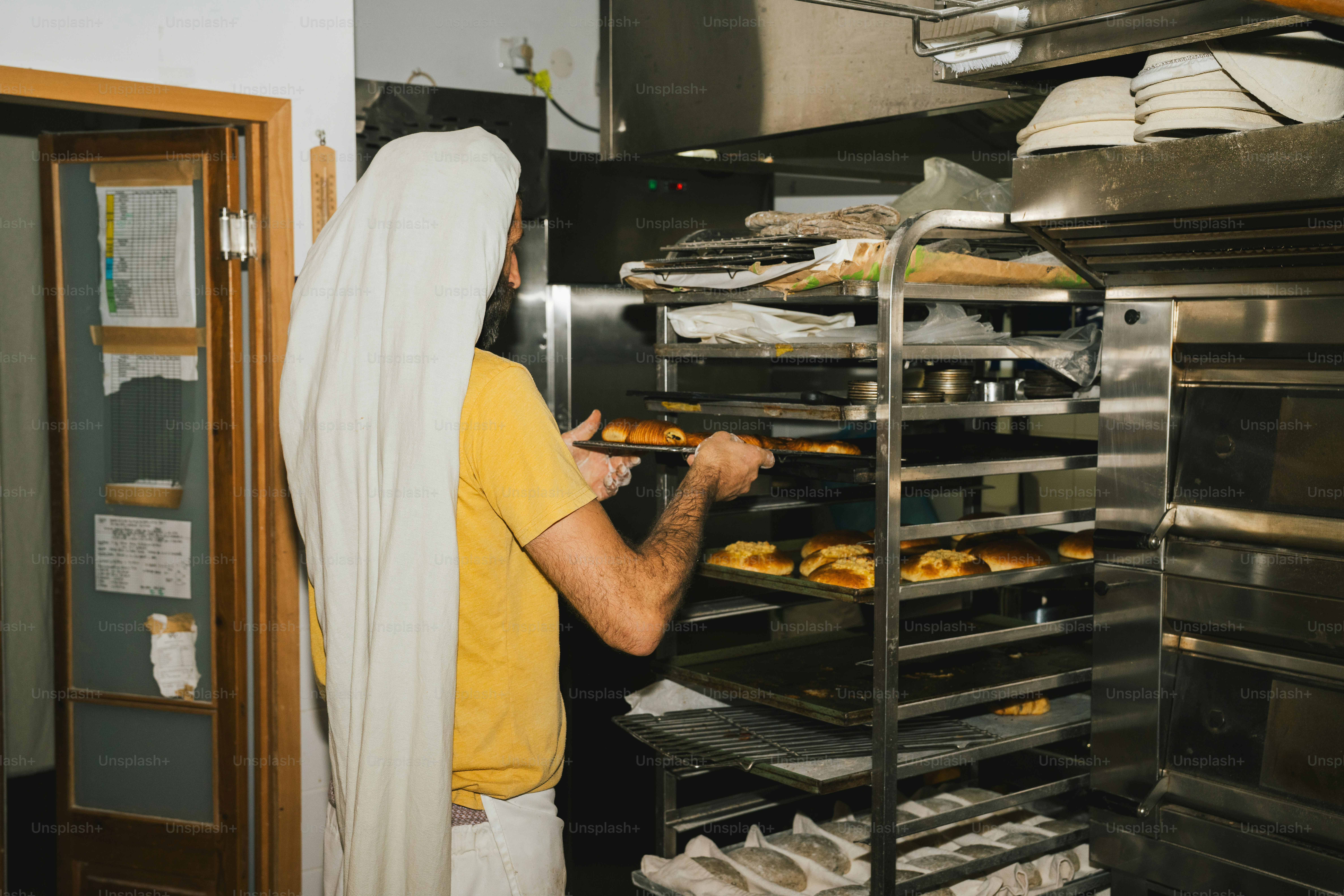 Baker placing tray of pastries into industrial oven