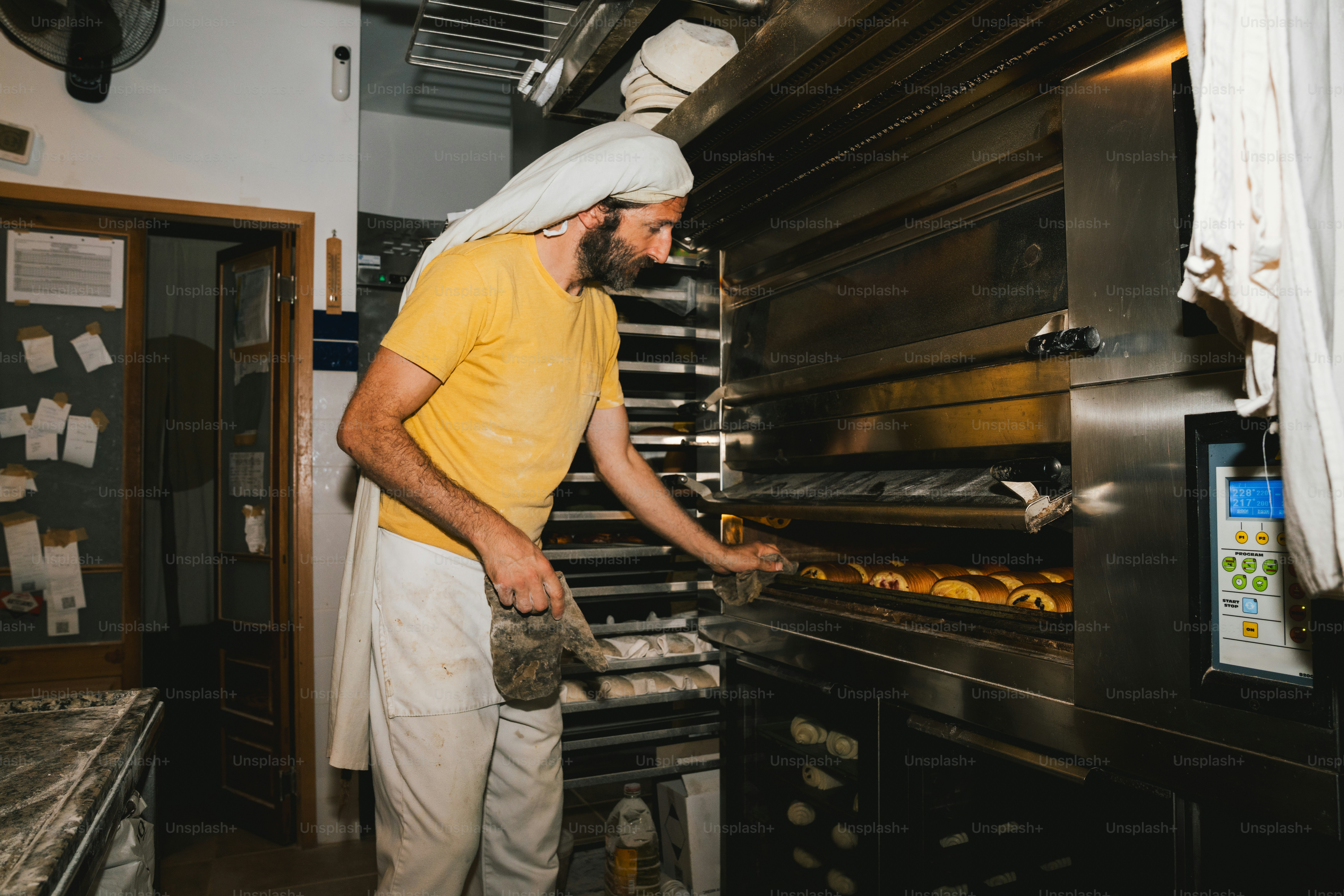 Bäcker, der Brot in einen großen Industrieofen legt.