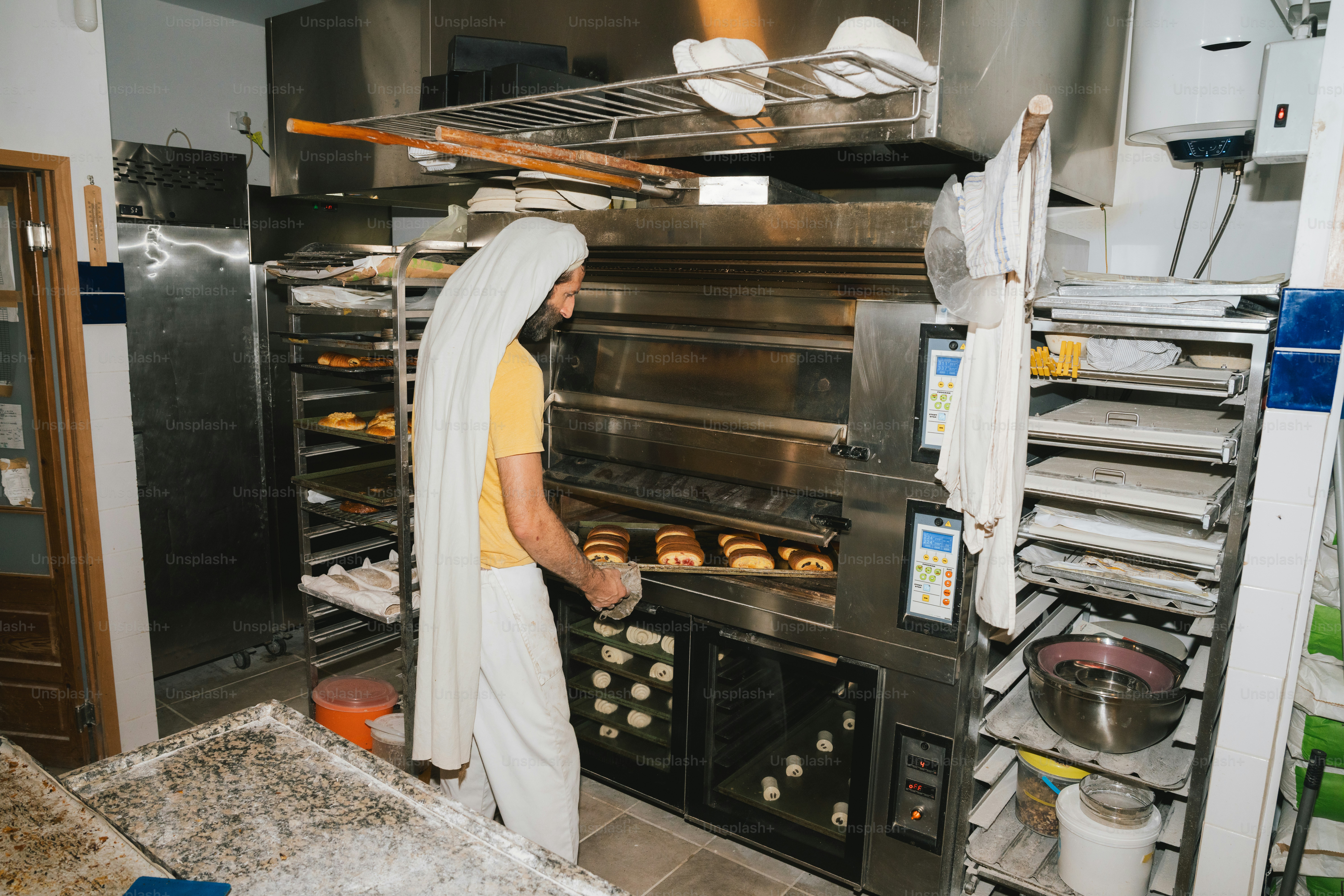 Bäcker nimmt frisches Brot aus dem Industrieofen.