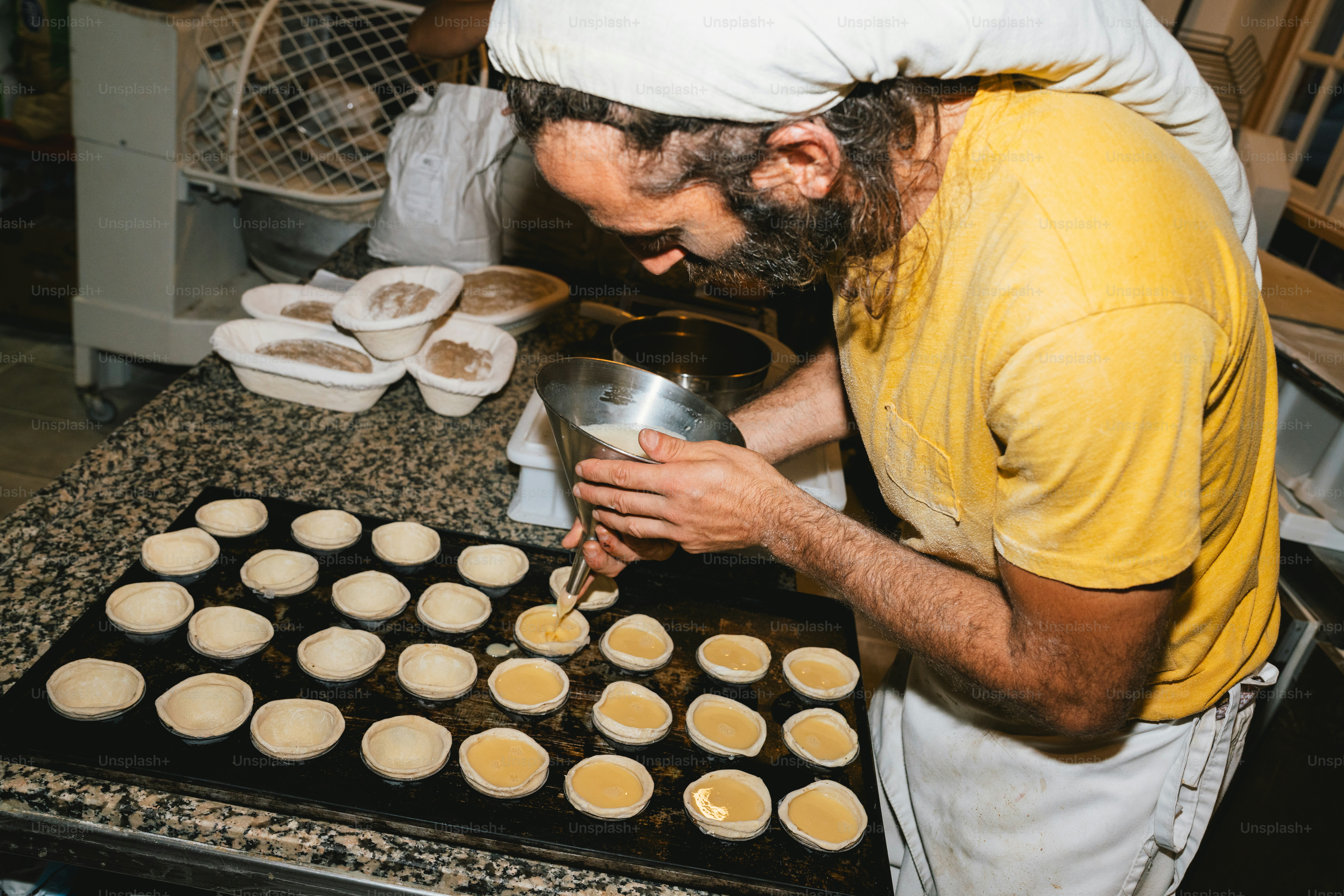 Baker places tray of pastries into oven. photo – Bakery Image on Unsplash