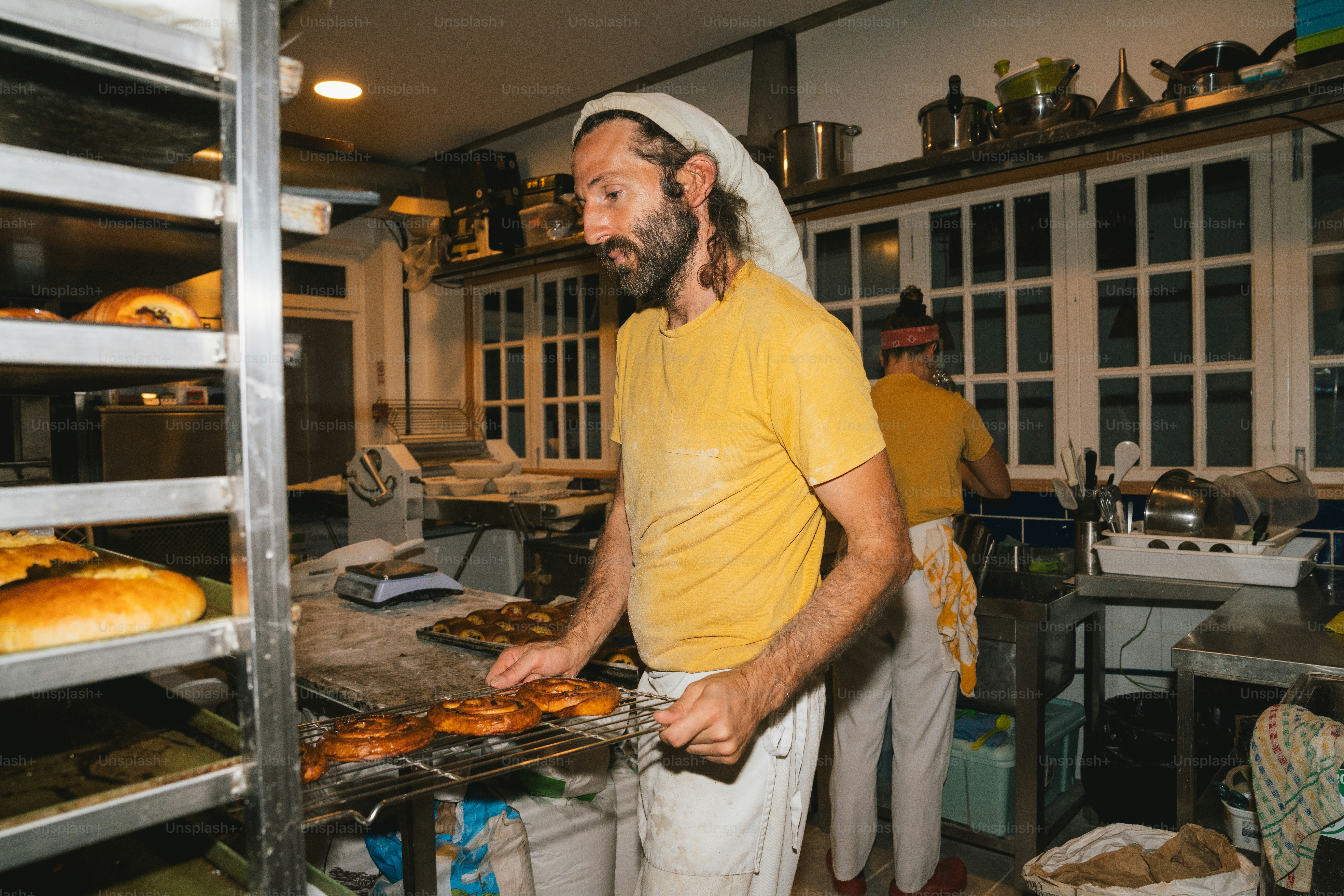 Baker placing pastries on cooling rack in bakery.