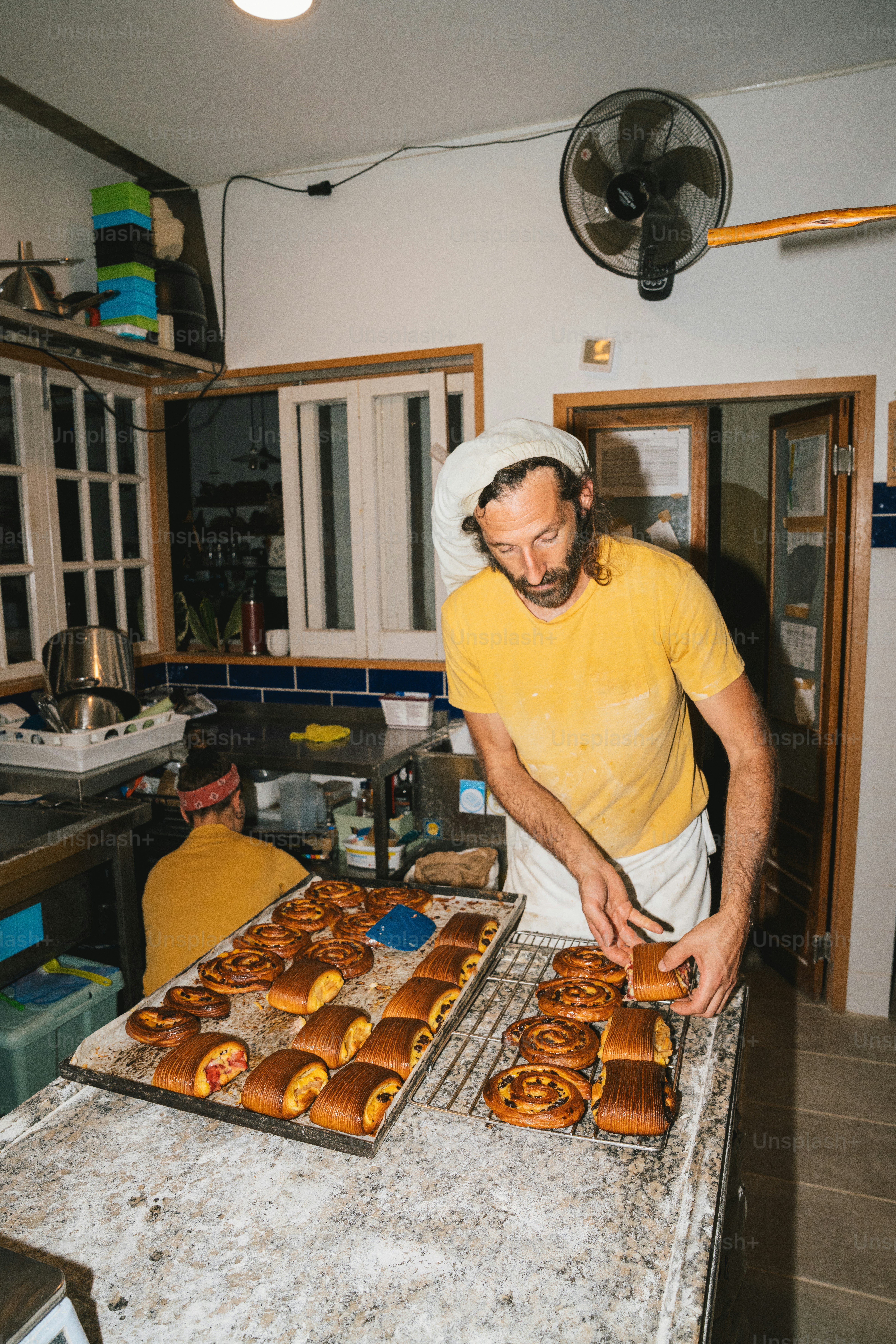 Baker places tray of pastries into oven. photo – Bakery Image on Unsplash