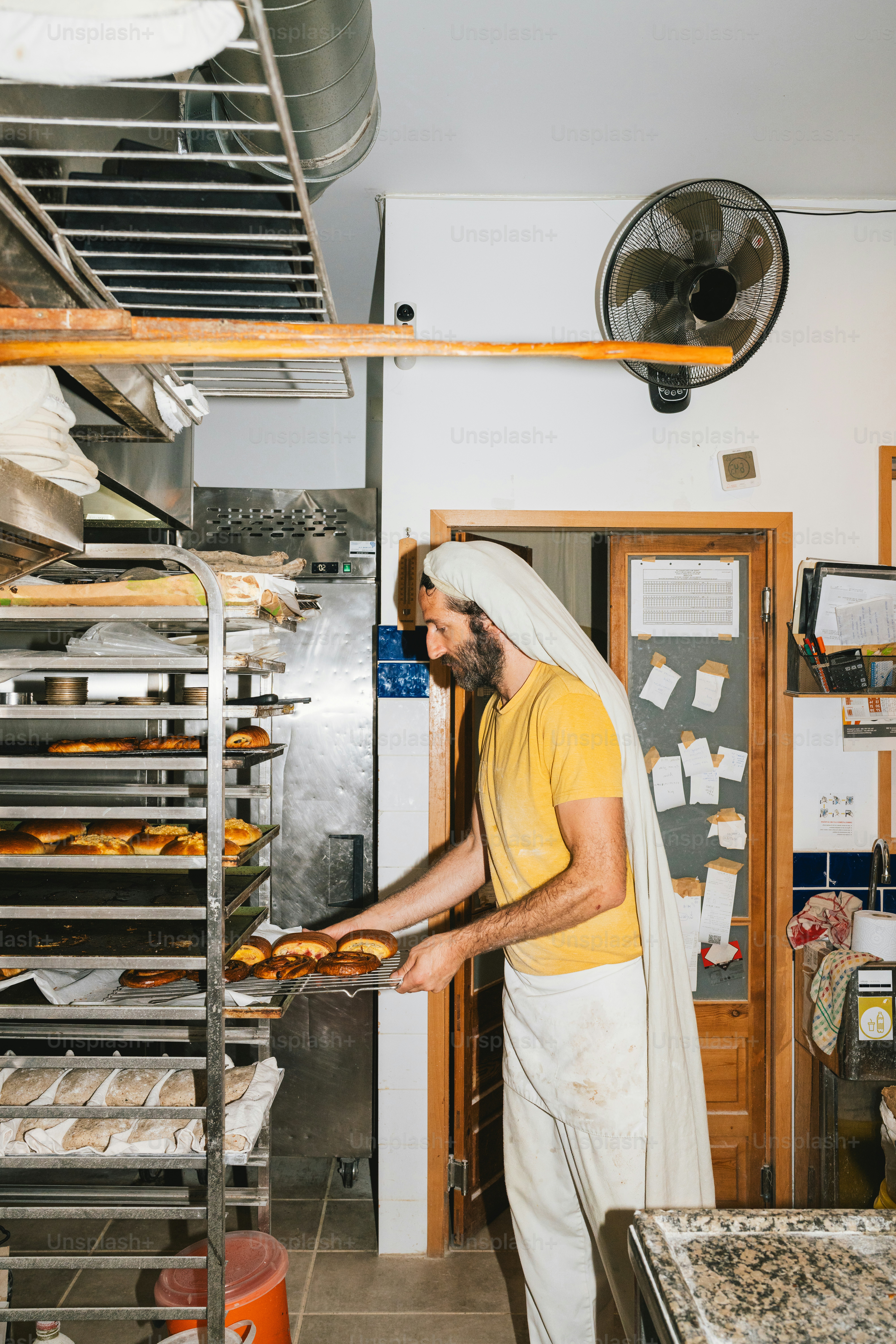 Baker places tray of pastries into oven. photo – Bakery Image on Unsplash