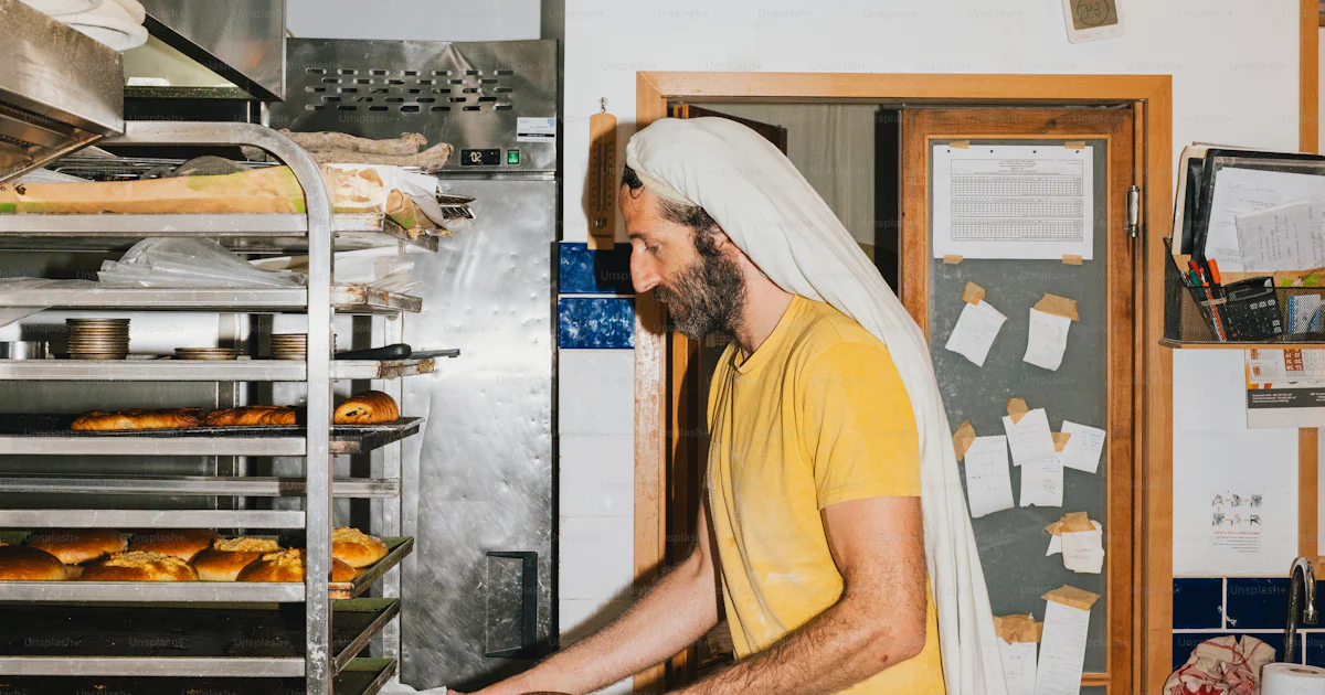 Baker places tray of pastries into oven. photo – Bakery Image on Unsplash
