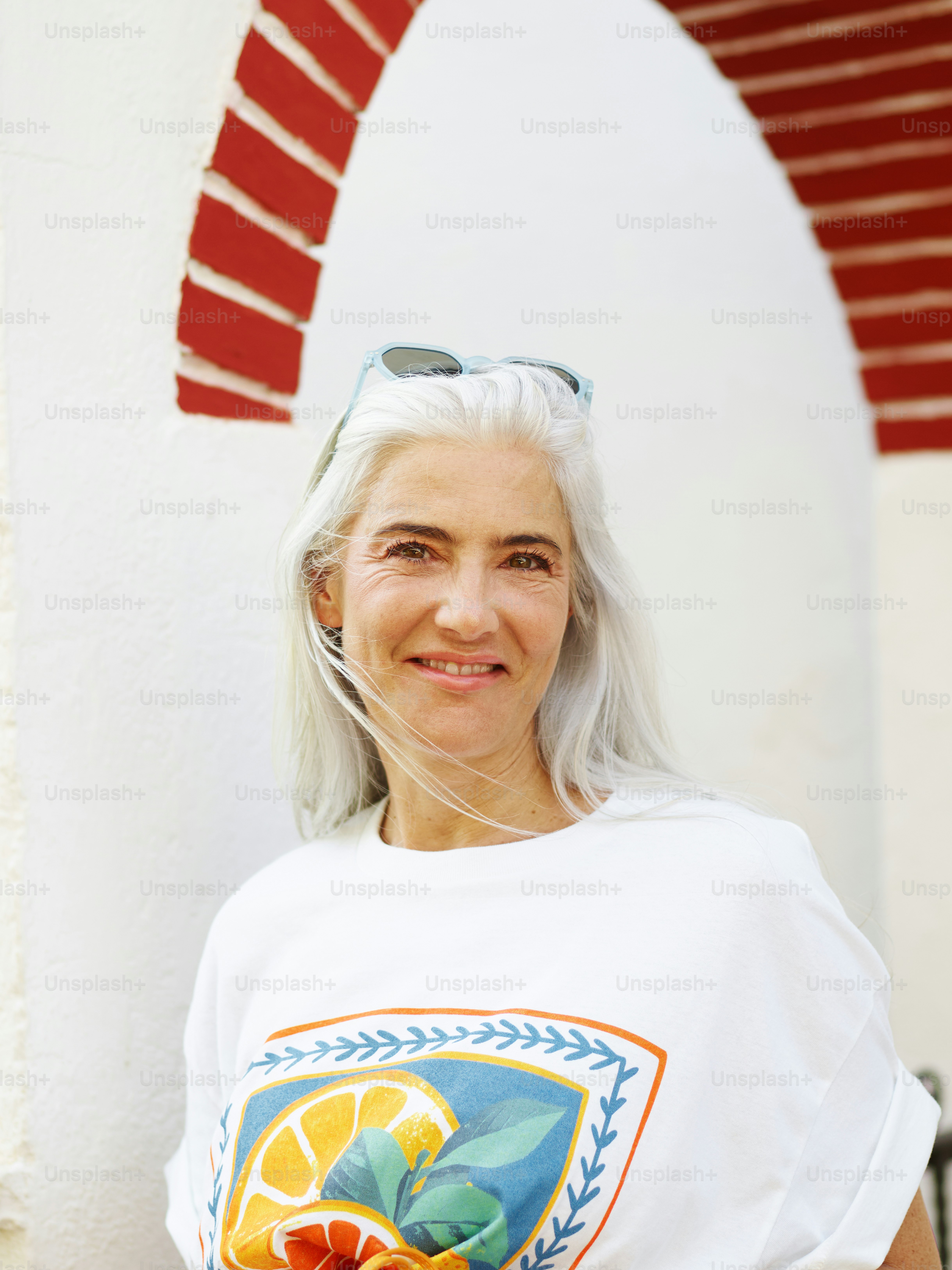 Woman with gray hair smiles under archway