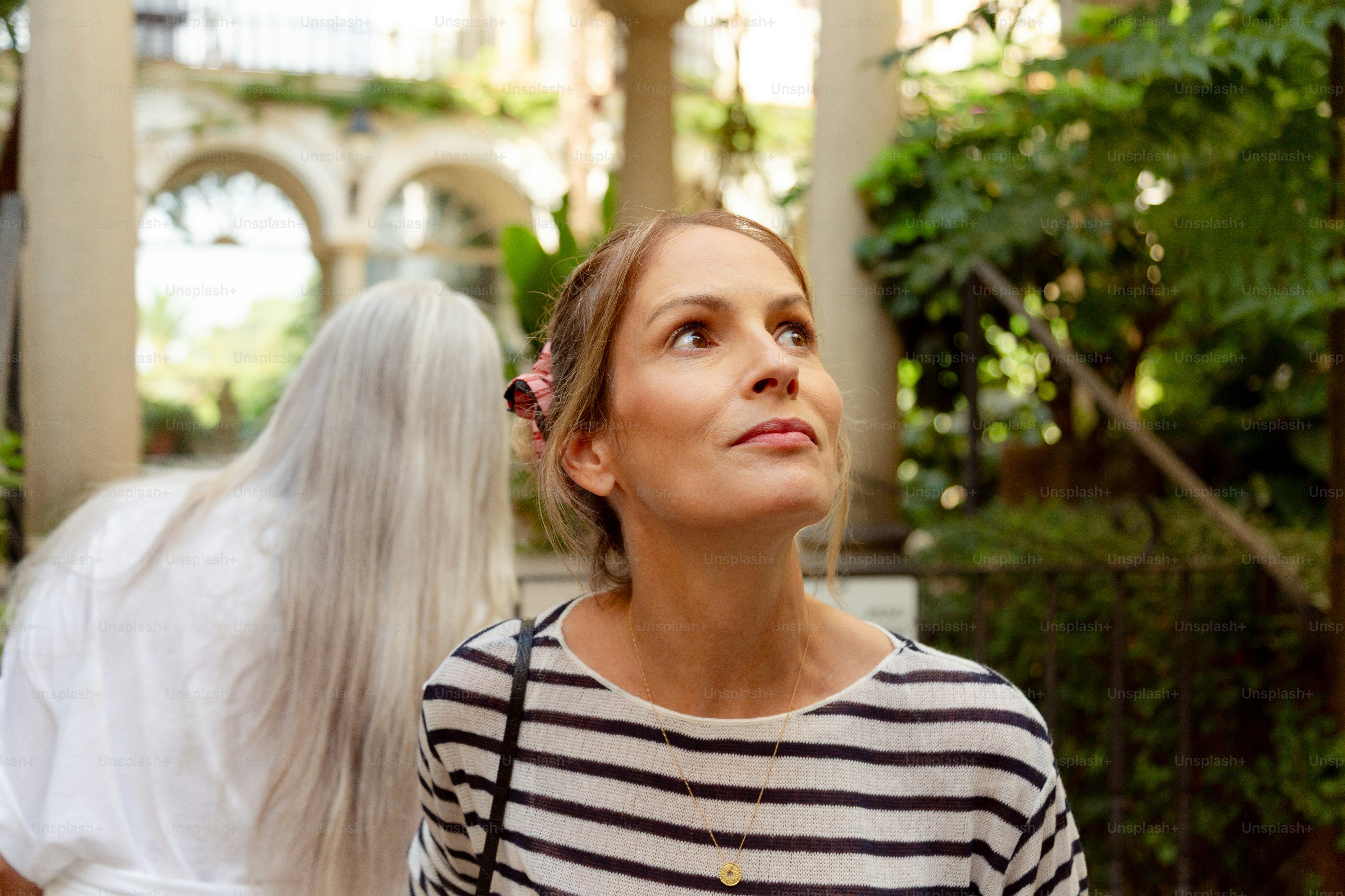 Woman looking up in a courtyard with greenery.