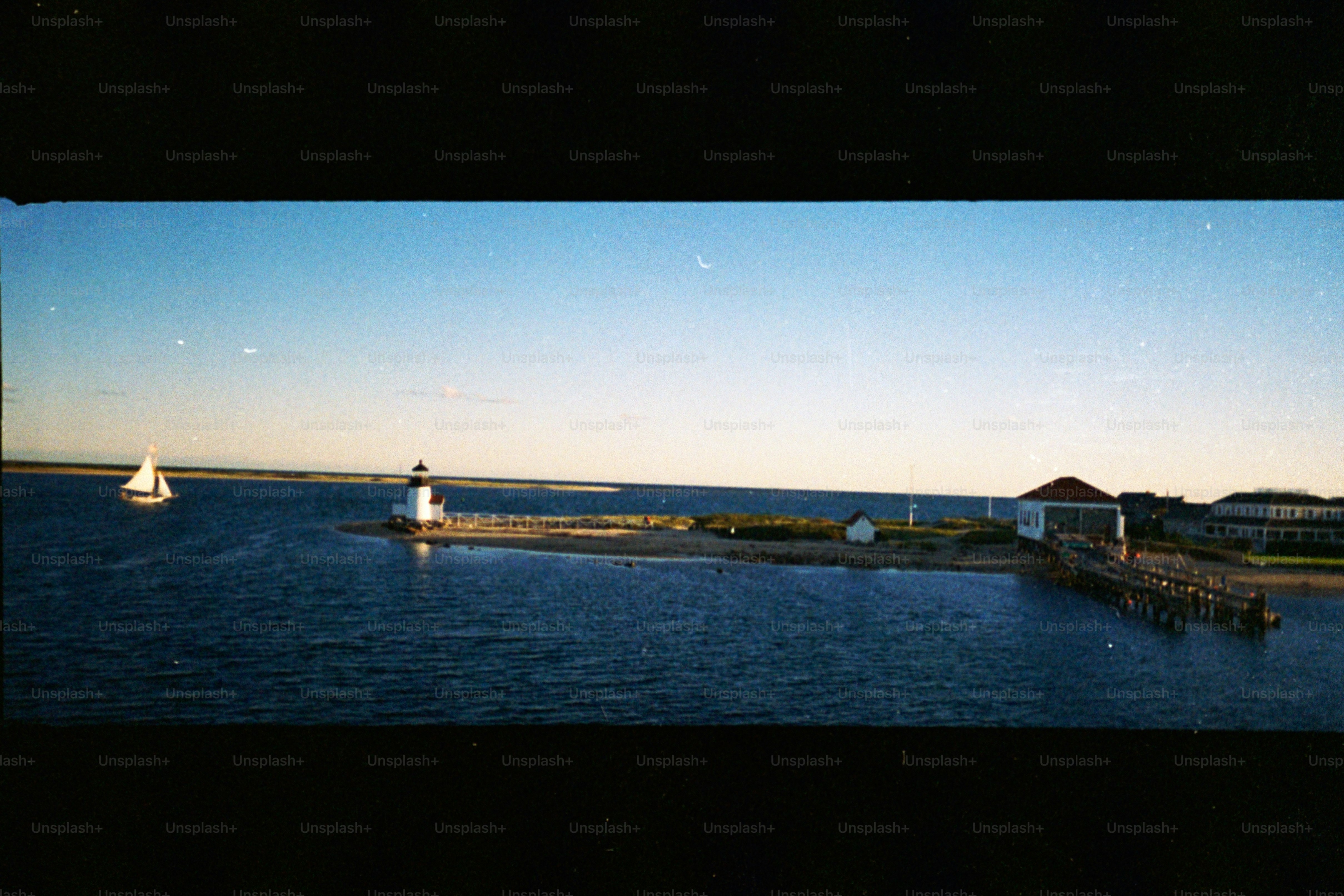 Veleiro perto do farol e edifícios em um cais.