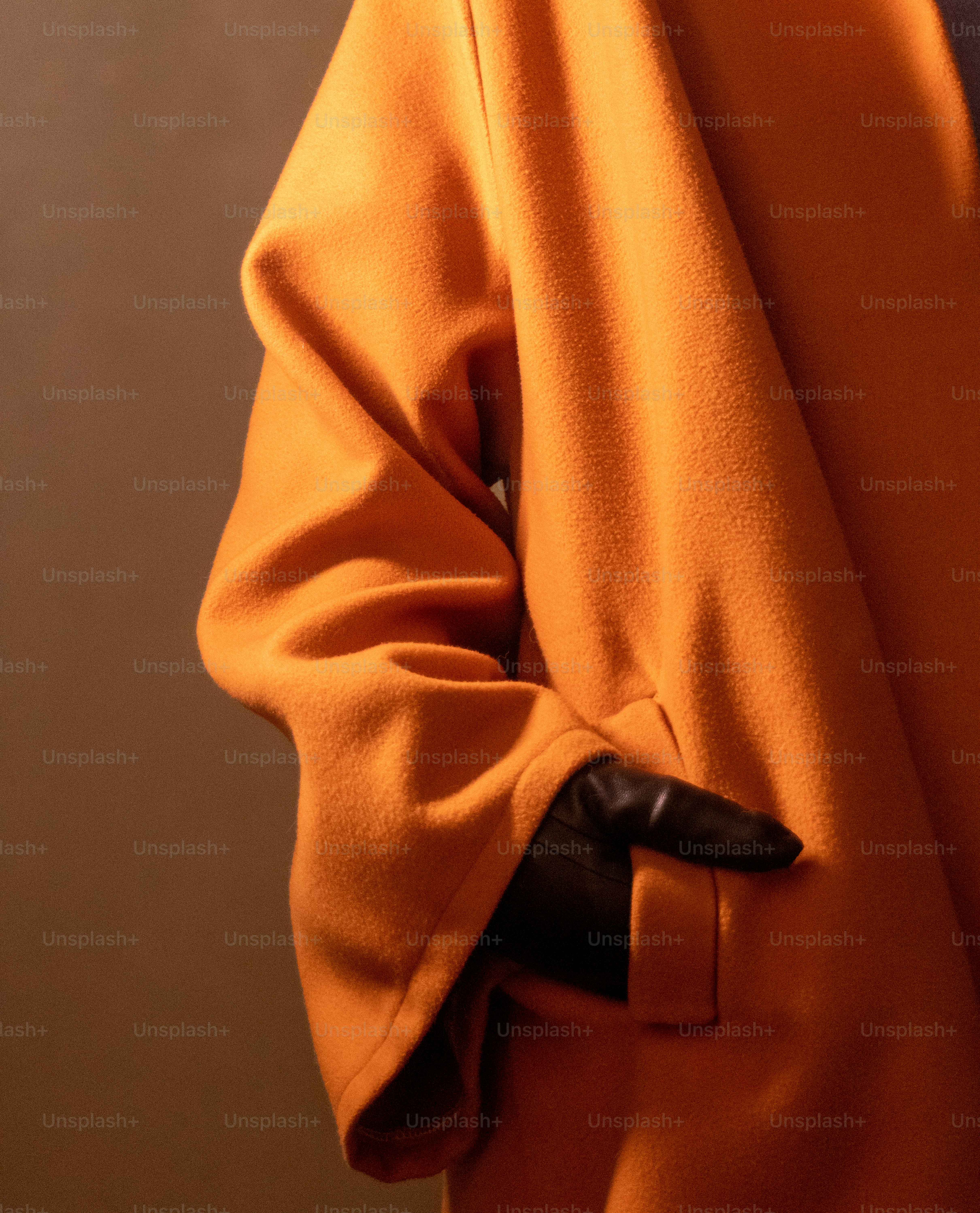 A person in an orange coat with black gloves.