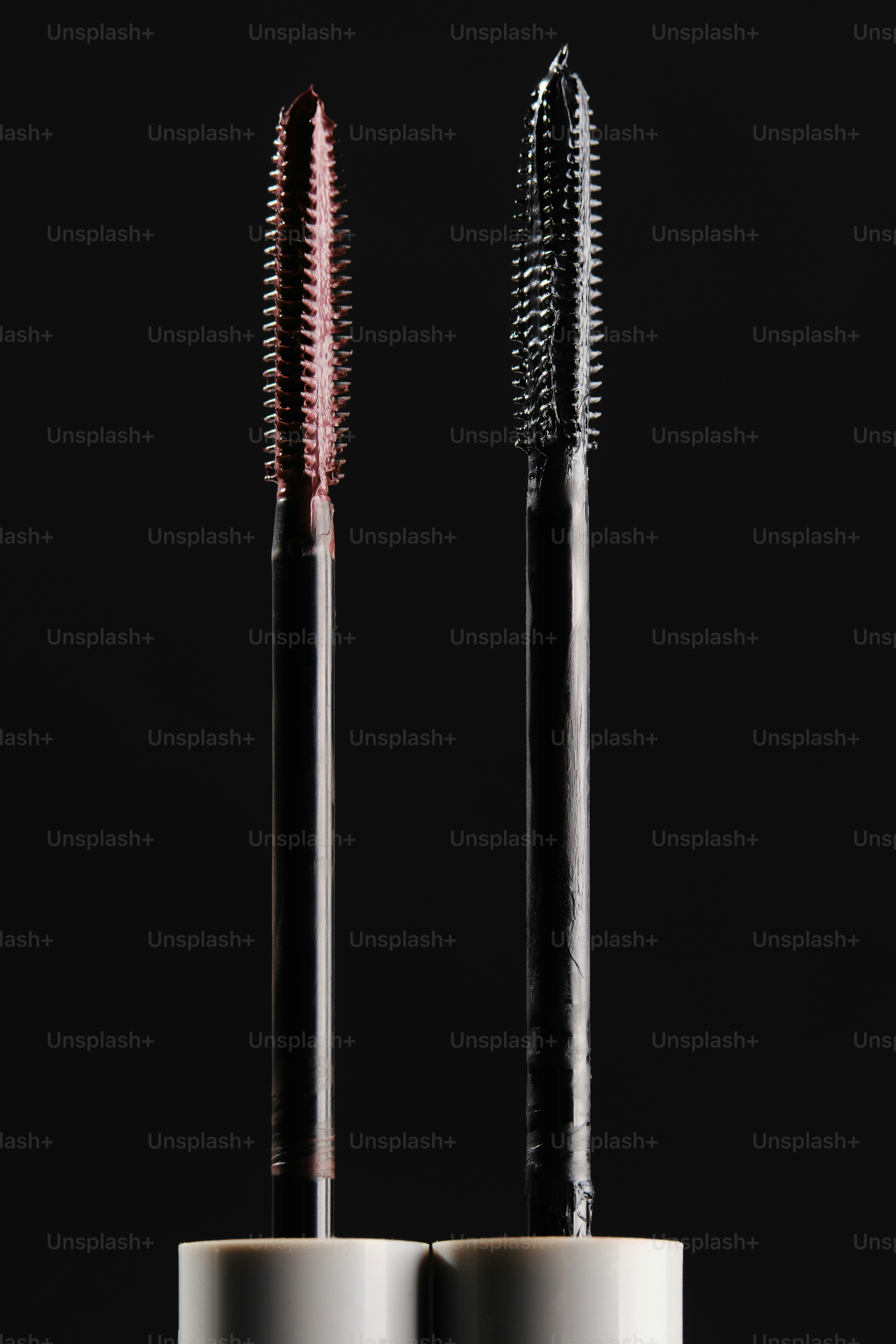 Two mascara wands with black and pink bristles.