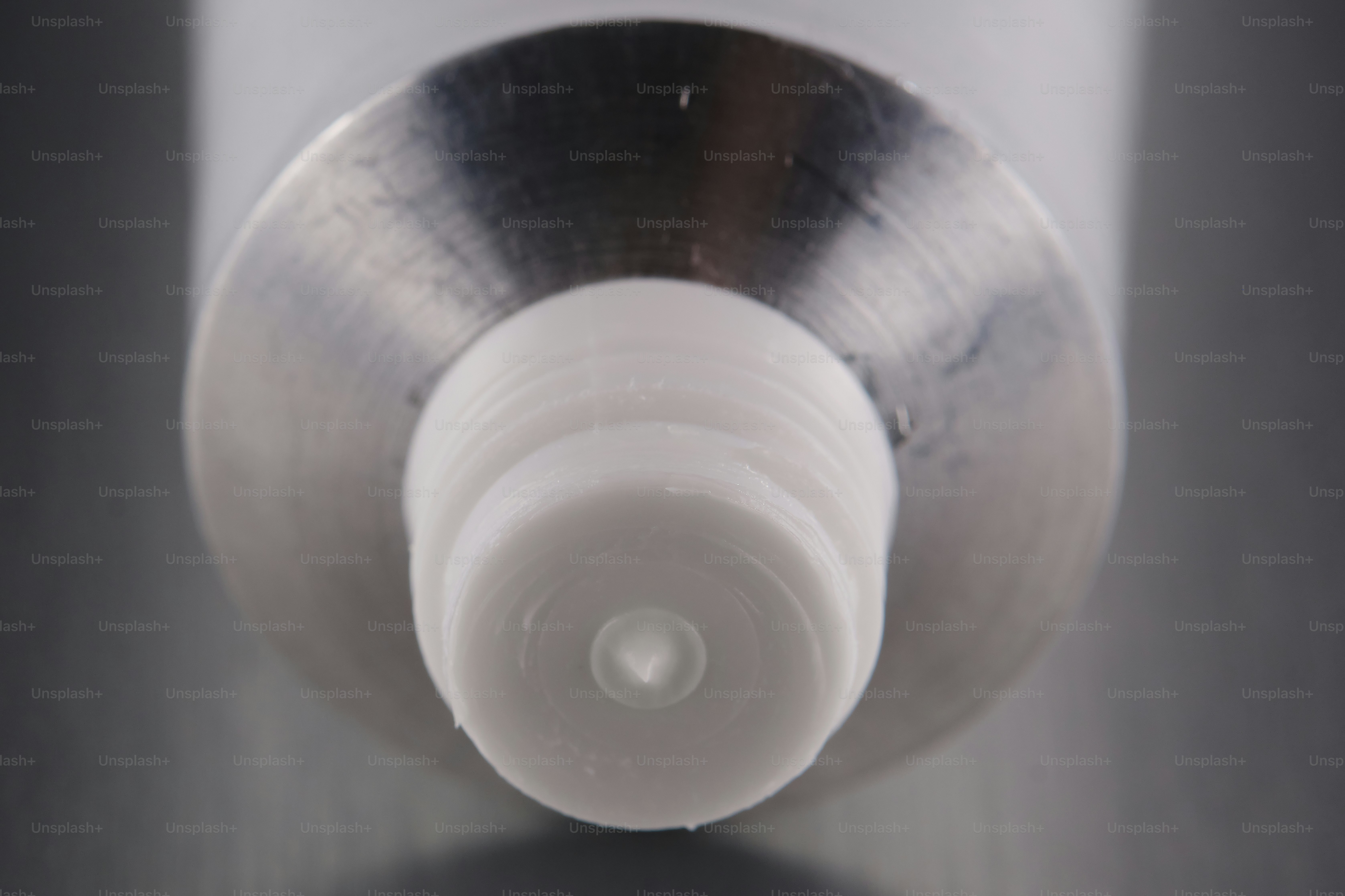 Close-up of a capped metal tube on a gray surface