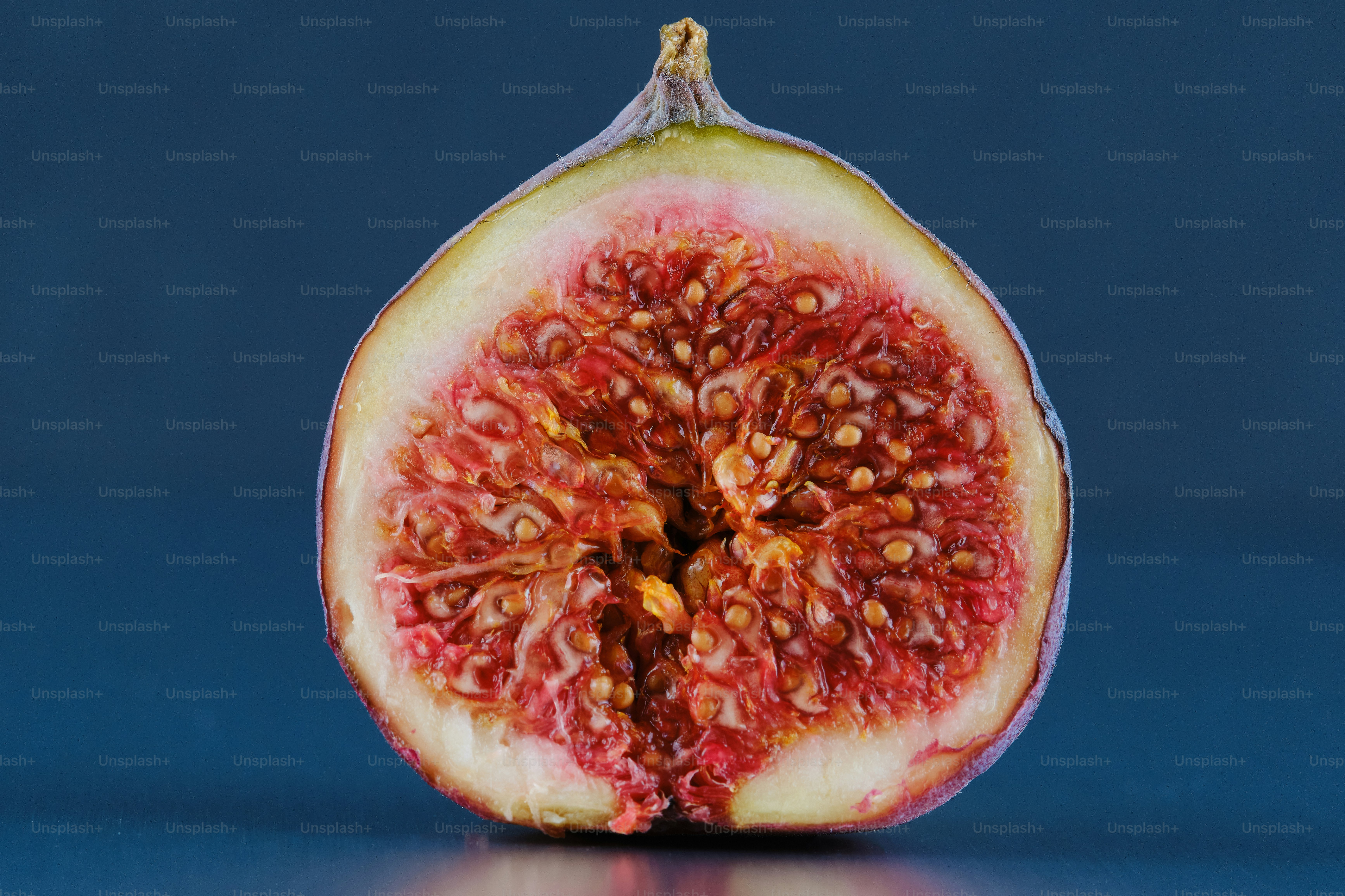 A halved fresh fig with red pulp and seeds. photo – Fruit Image on Unsplash
