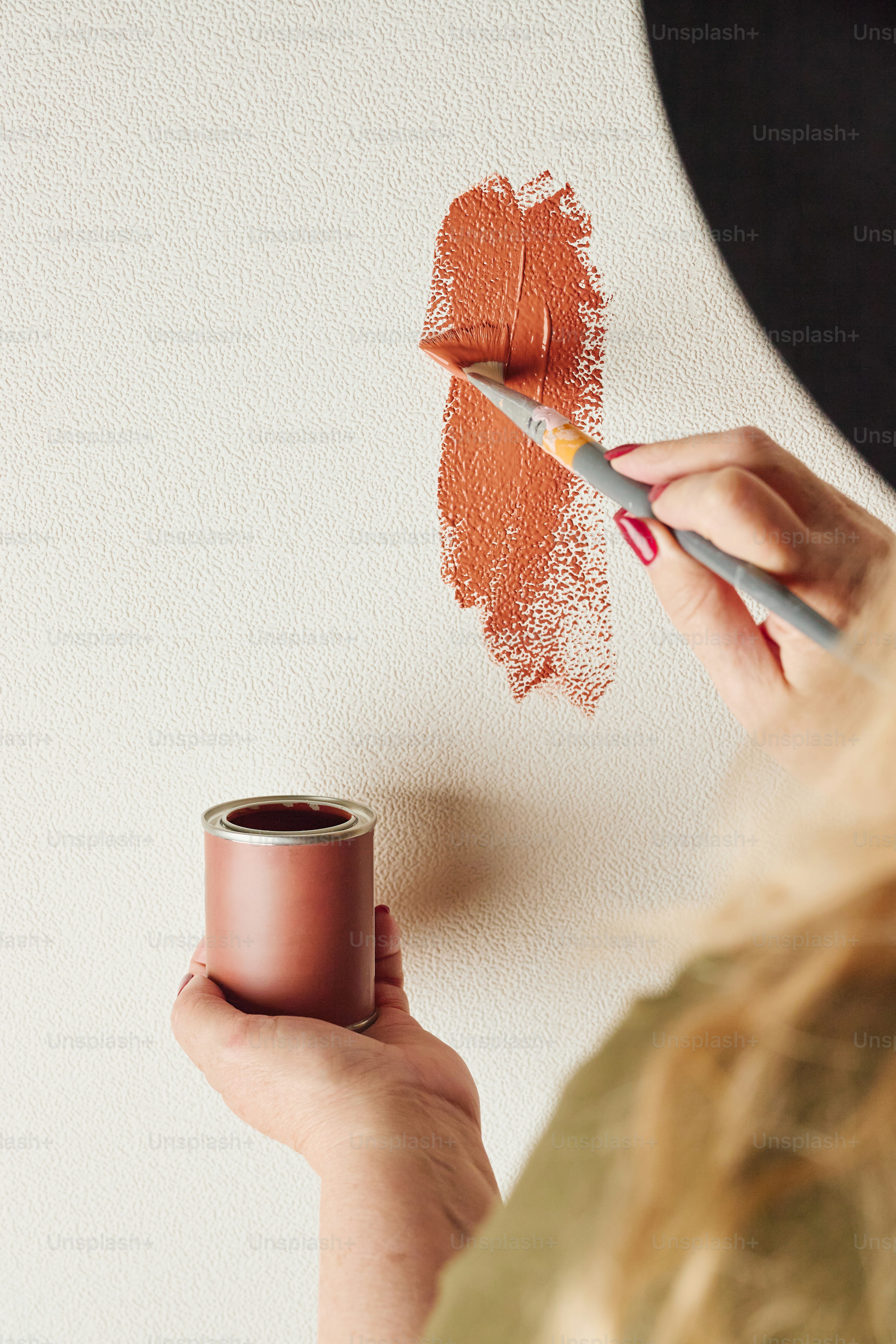 Mão pintando uma parede com cor de terracota