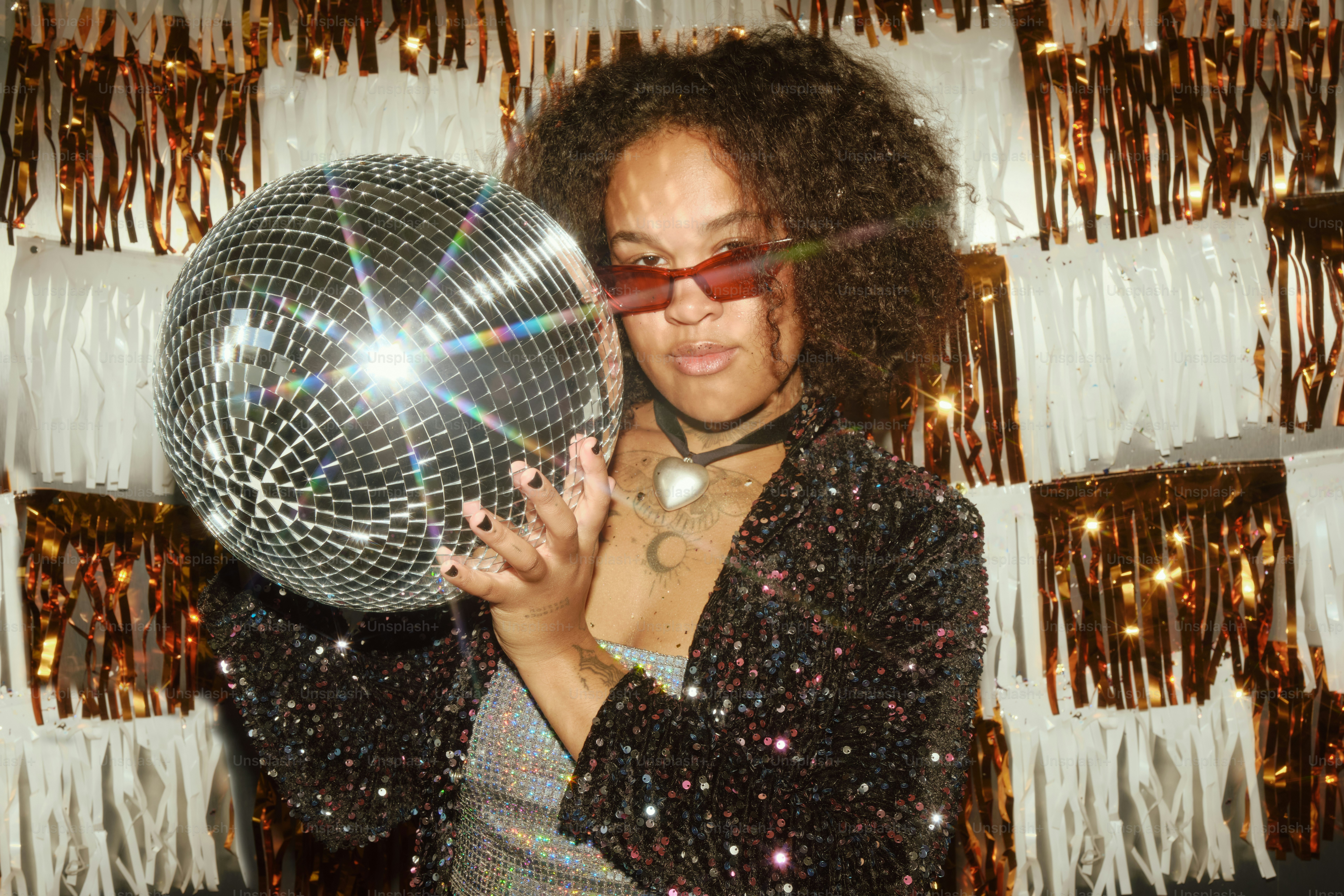Woman holding a disco ball with a festive background.