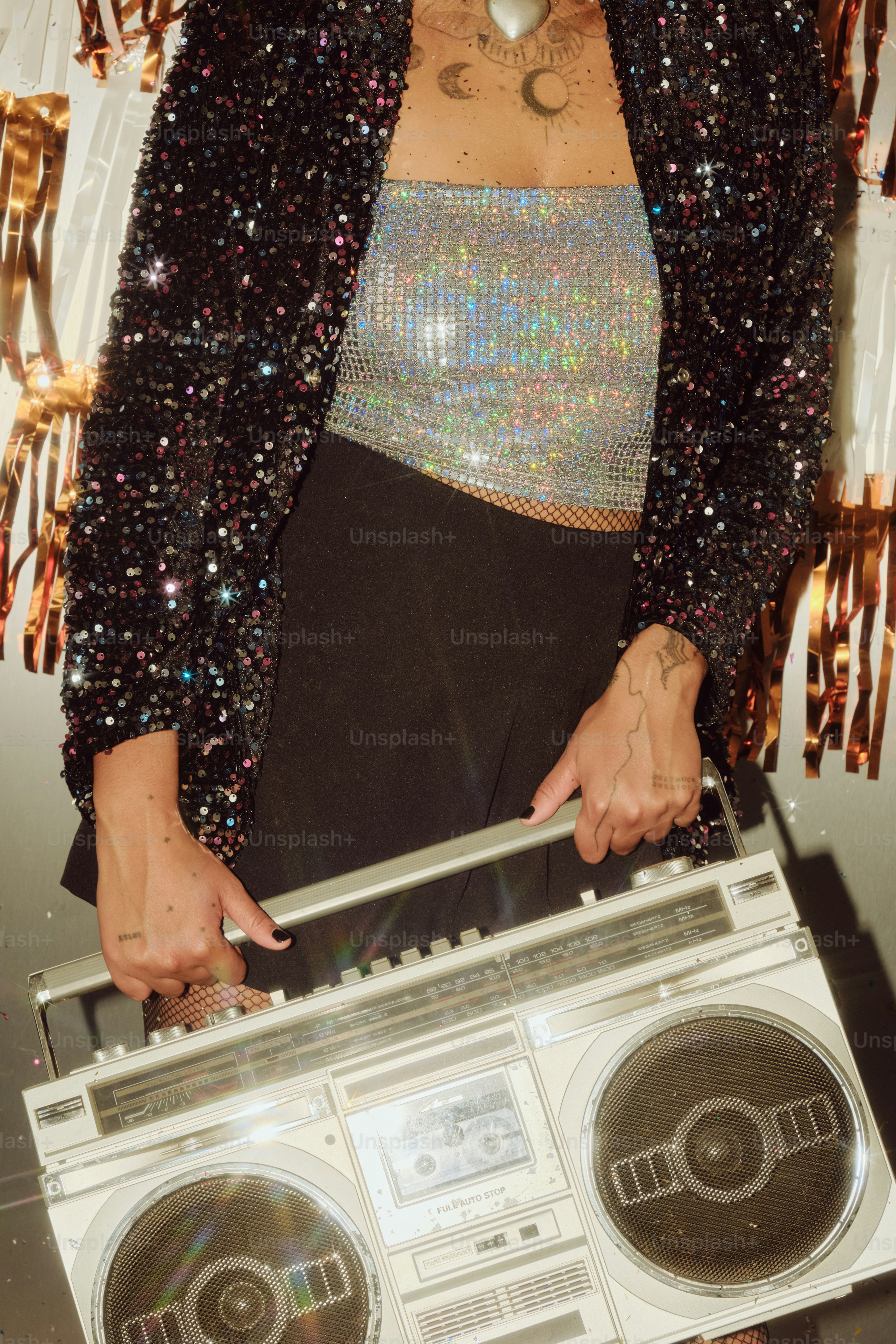 Wanita dengan jaket berkilau memegang boombox vintage