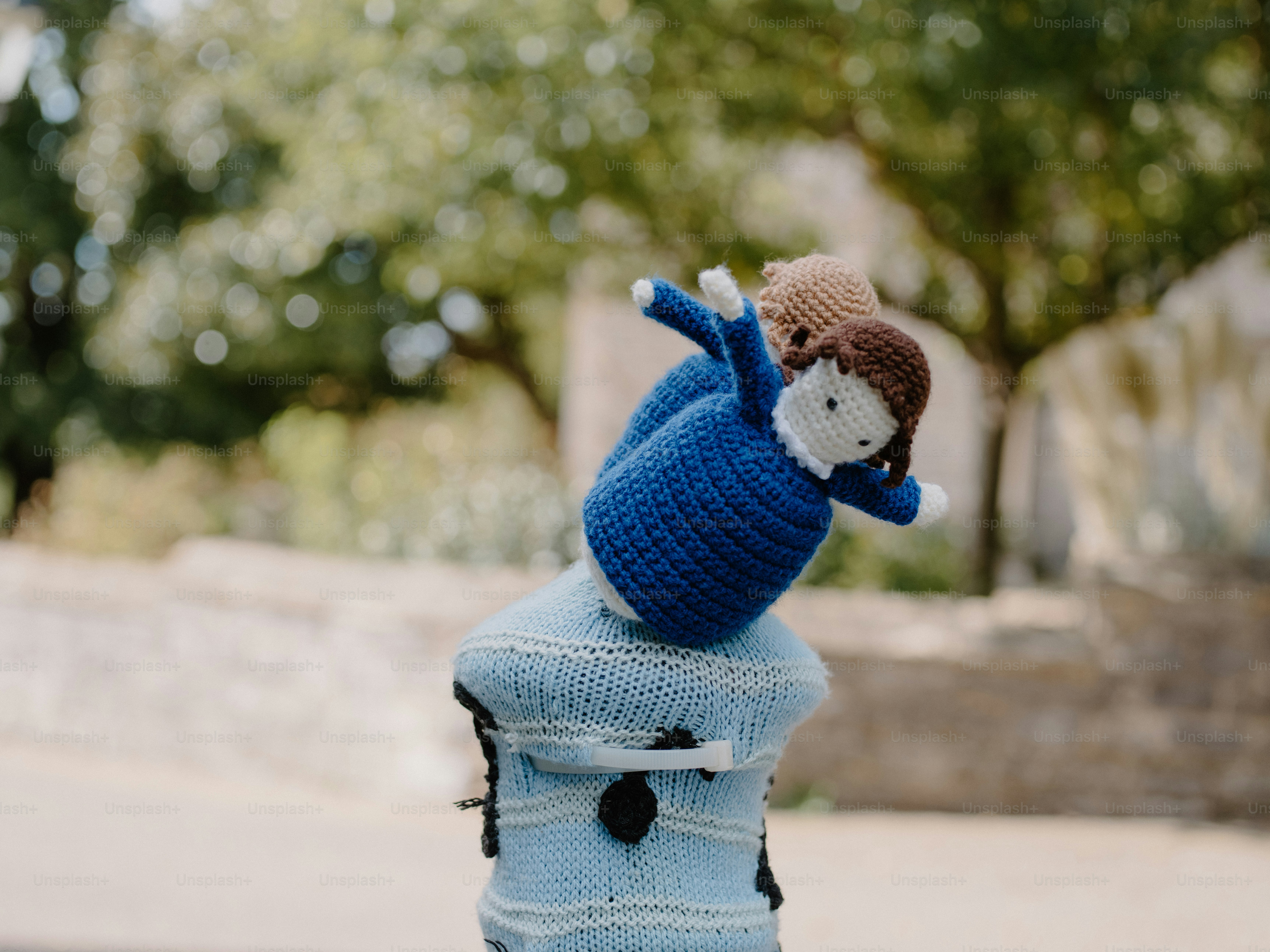 Two crocheted dolls on a blue knitted post.