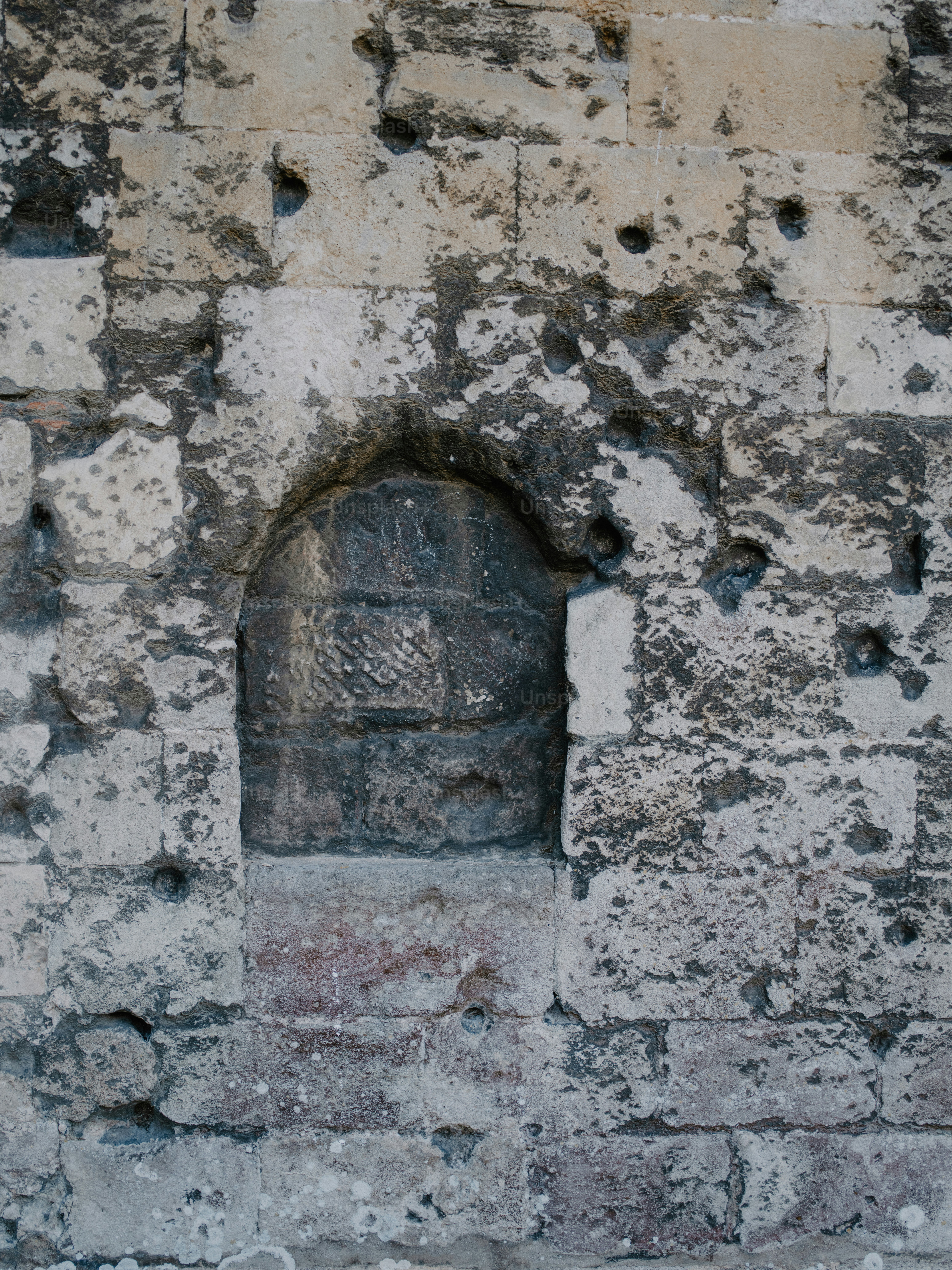 Rough stone wall with a small arched recess.