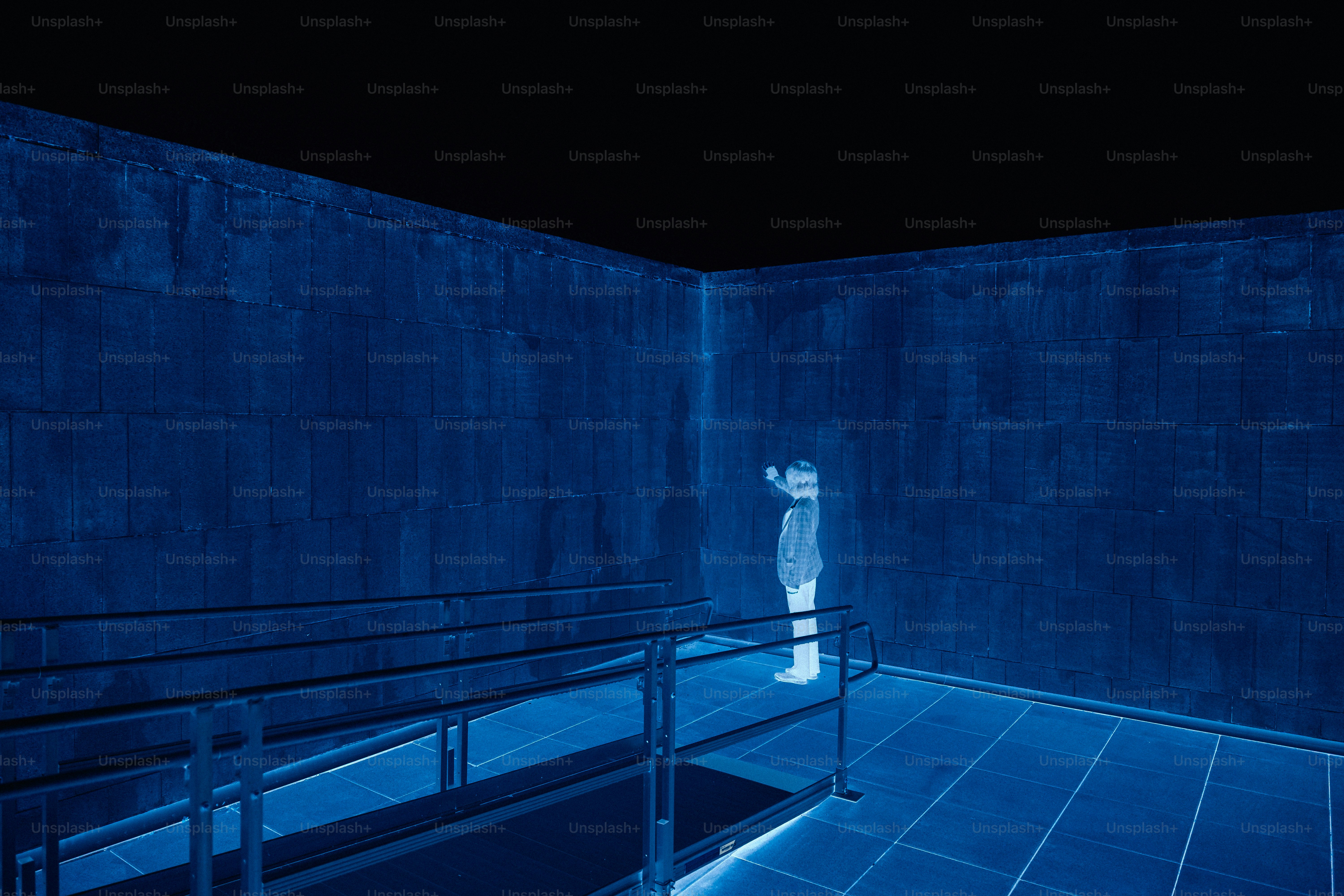 Man in a blue room looking up at the wall.