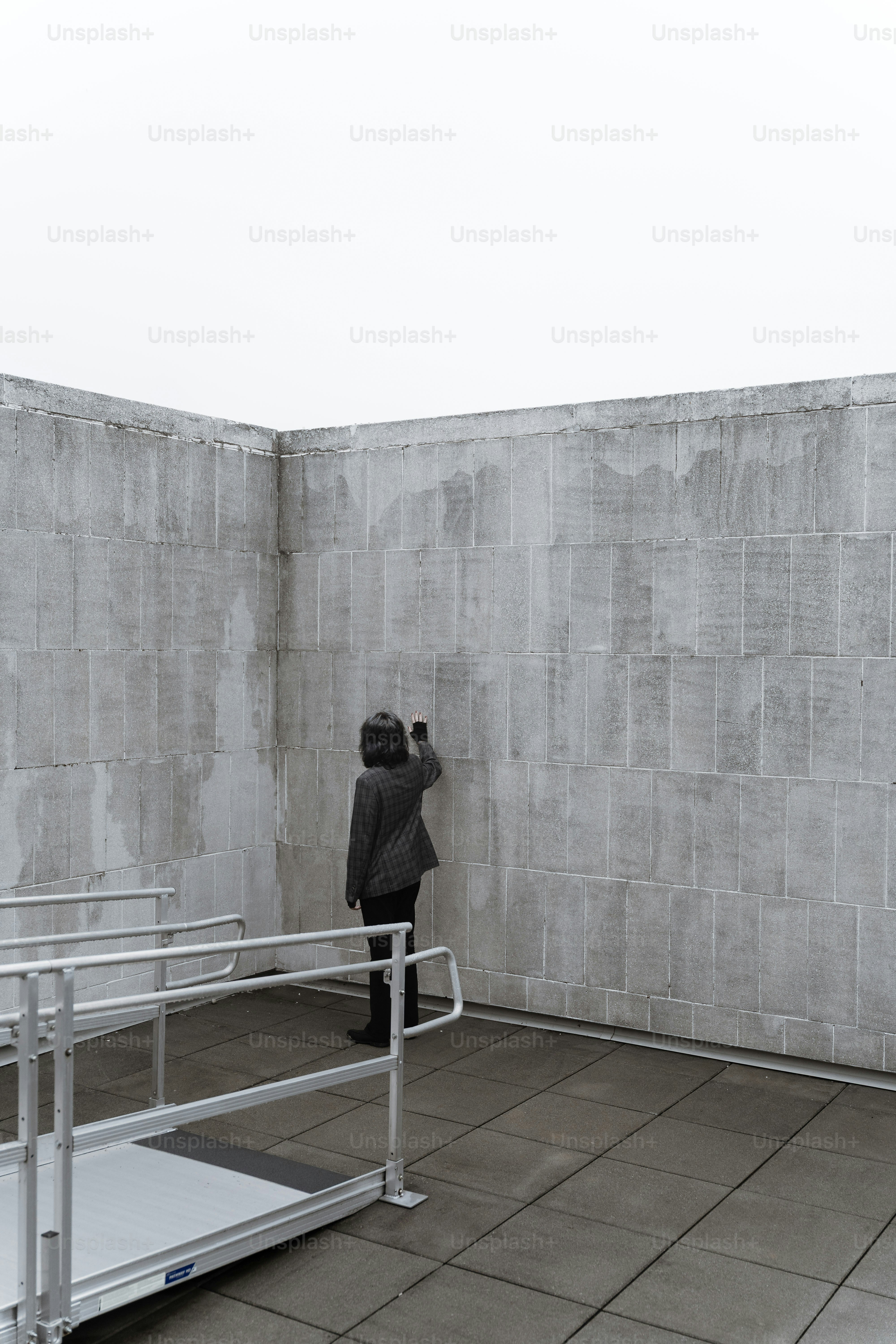 Person touching a textured wall under overcast sky.
