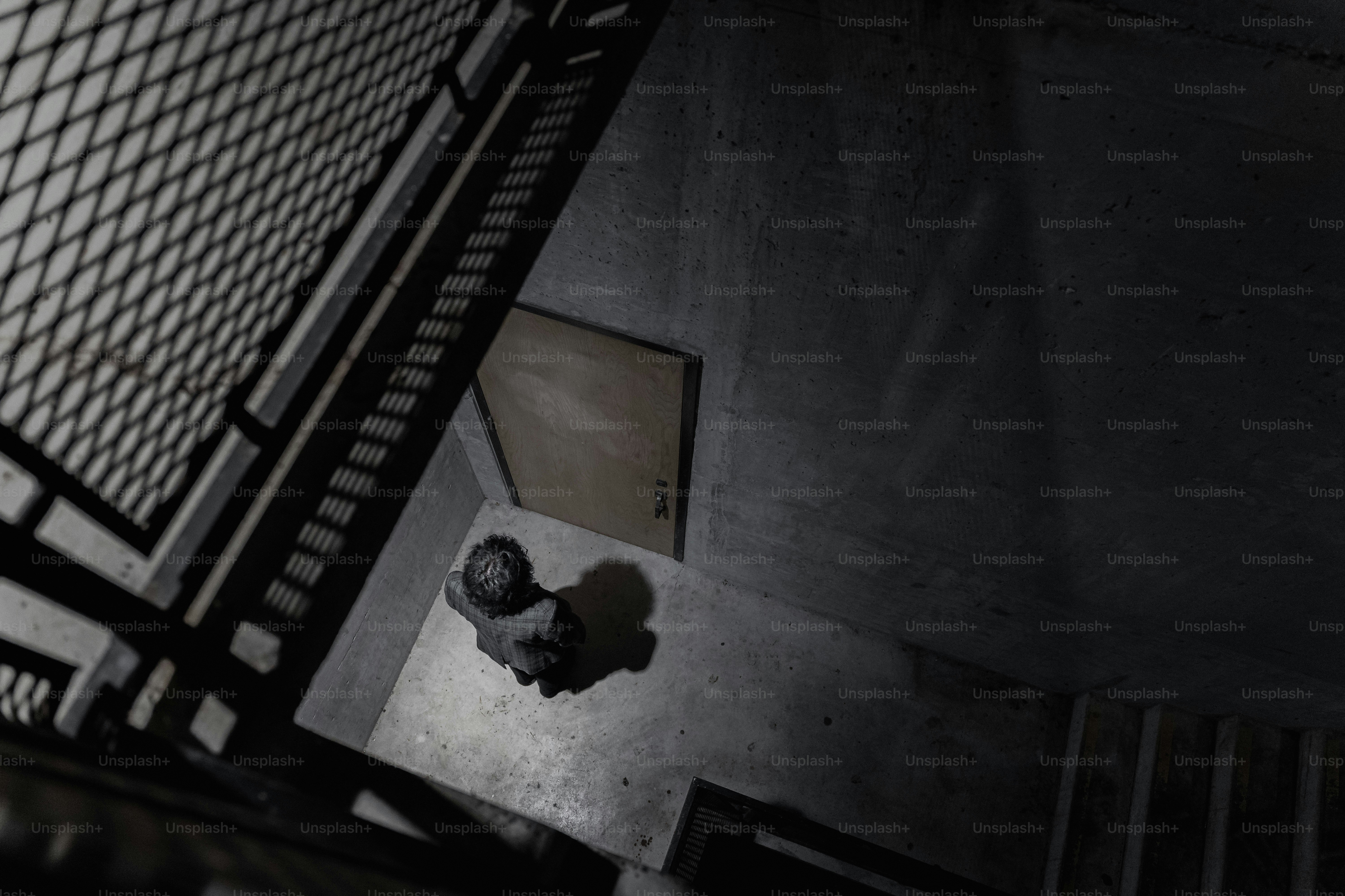 A person stands at the bottom of a stairwell.